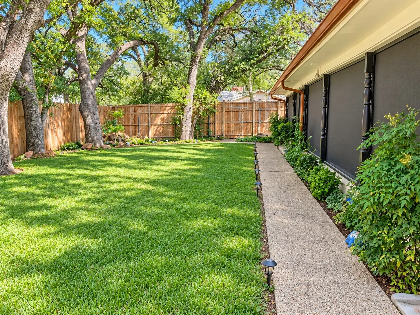 Expansive lawn with mature trees and a wood privacy fence