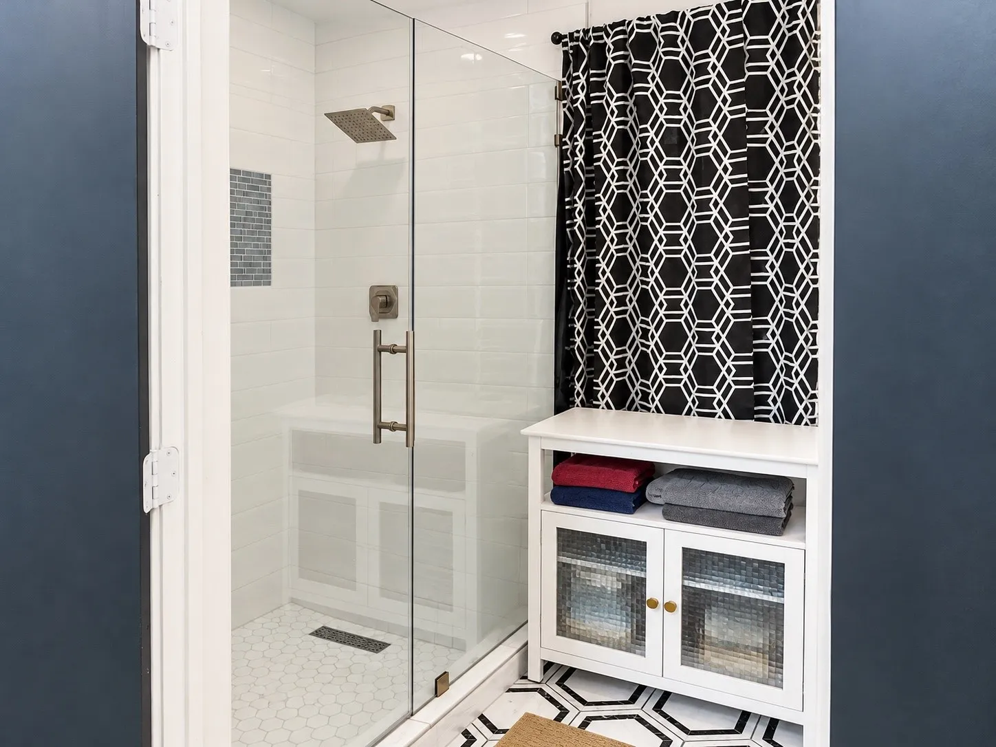 Glass-enclosed shower with white subway tile surround, integrated bench, and mosaic tile accent