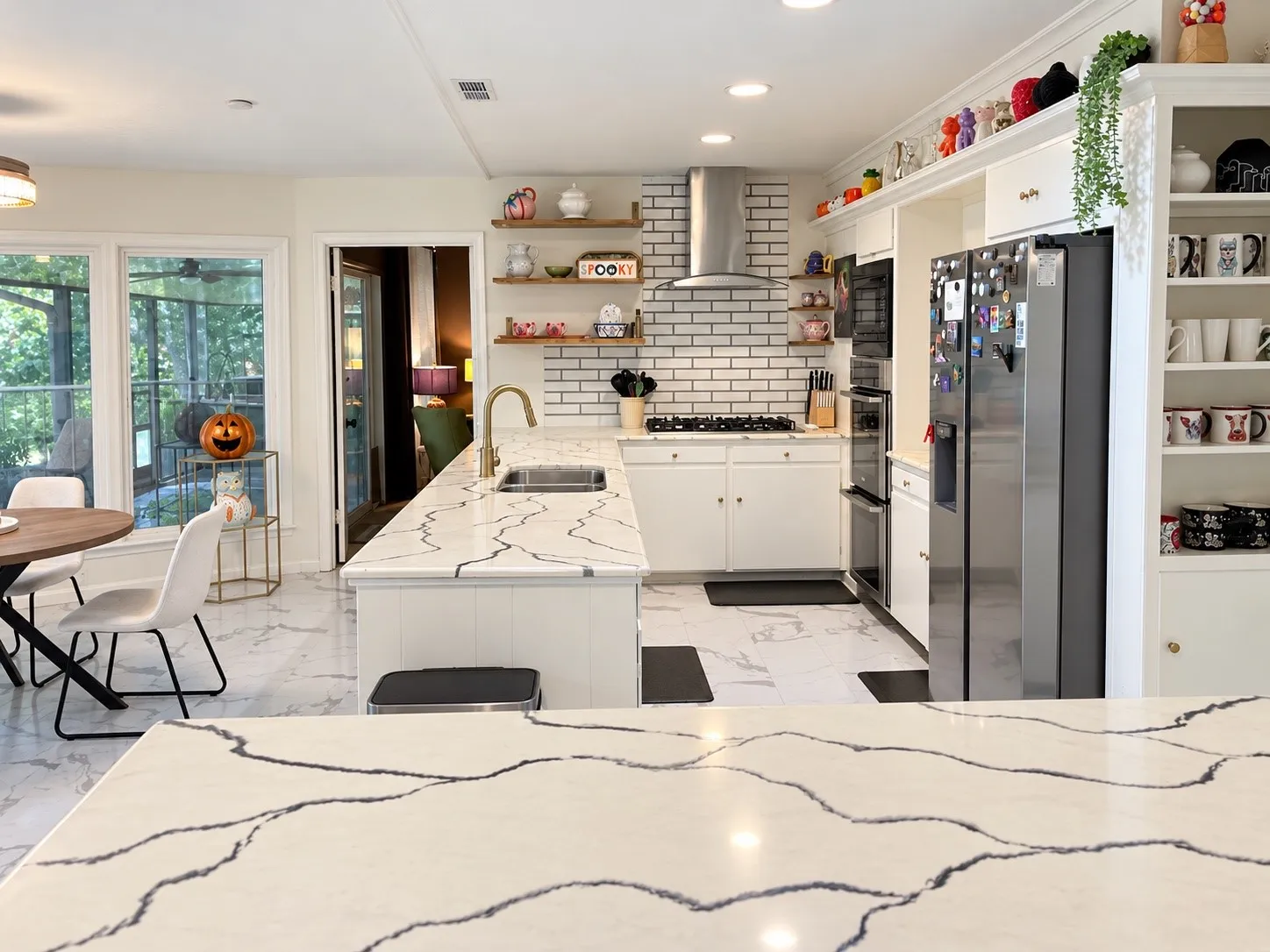 Kitchen featuring white cabinetry, patterned countertops, stainless steel appliances, and a tile backsplash