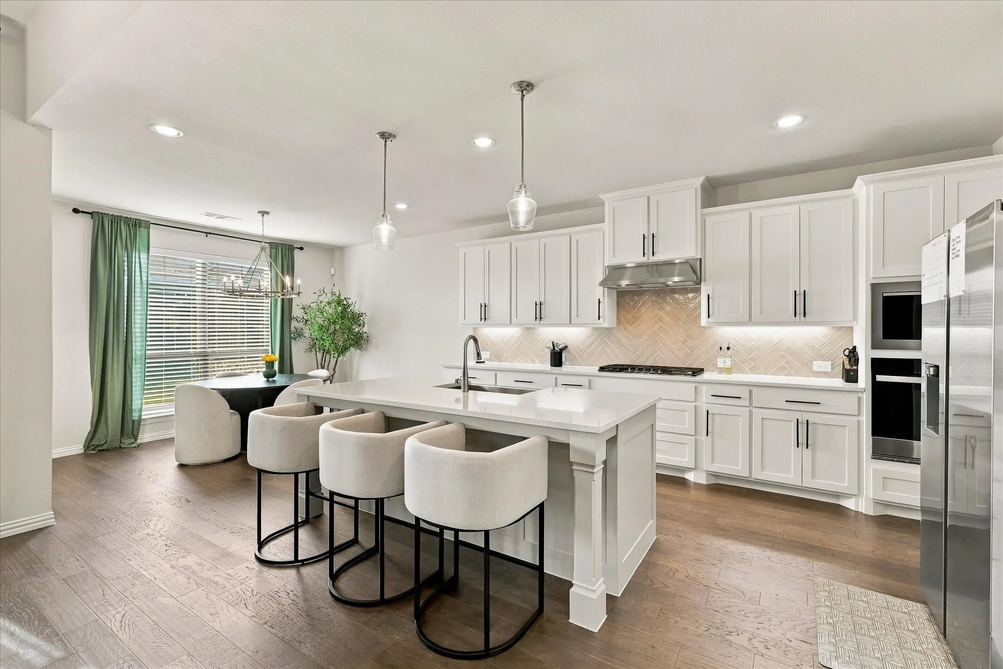 Kitchen featuring a large island with a countertop, shaker cabinetry, stainless steel appliances, a tile backsplash, and wood-finish flooring