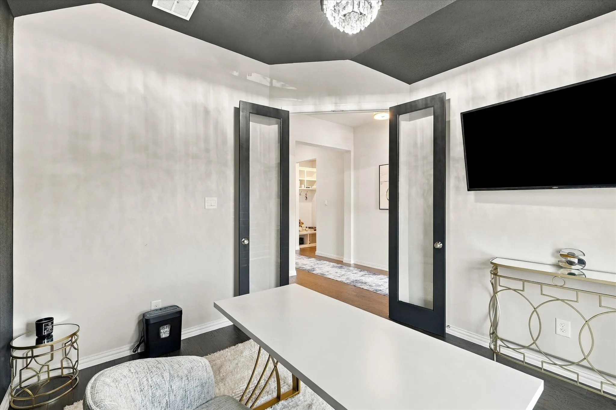 Dual opaque-paneled doors, dark wood-finish flooring, recessed lighting, and a crystal chandelier