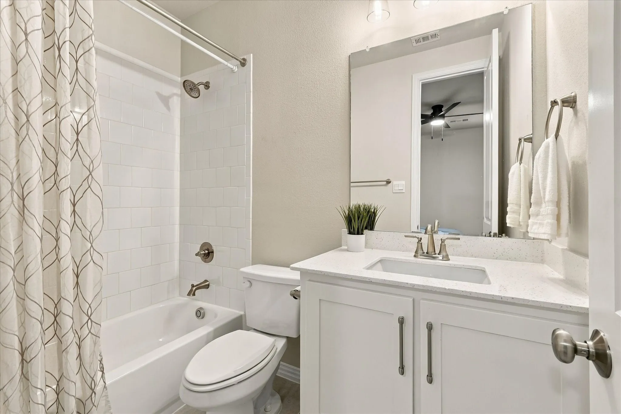 White vanity with dual cabinet doors, light-colored countertop, undermount sink, brushed nickel faucet, and a large mirror