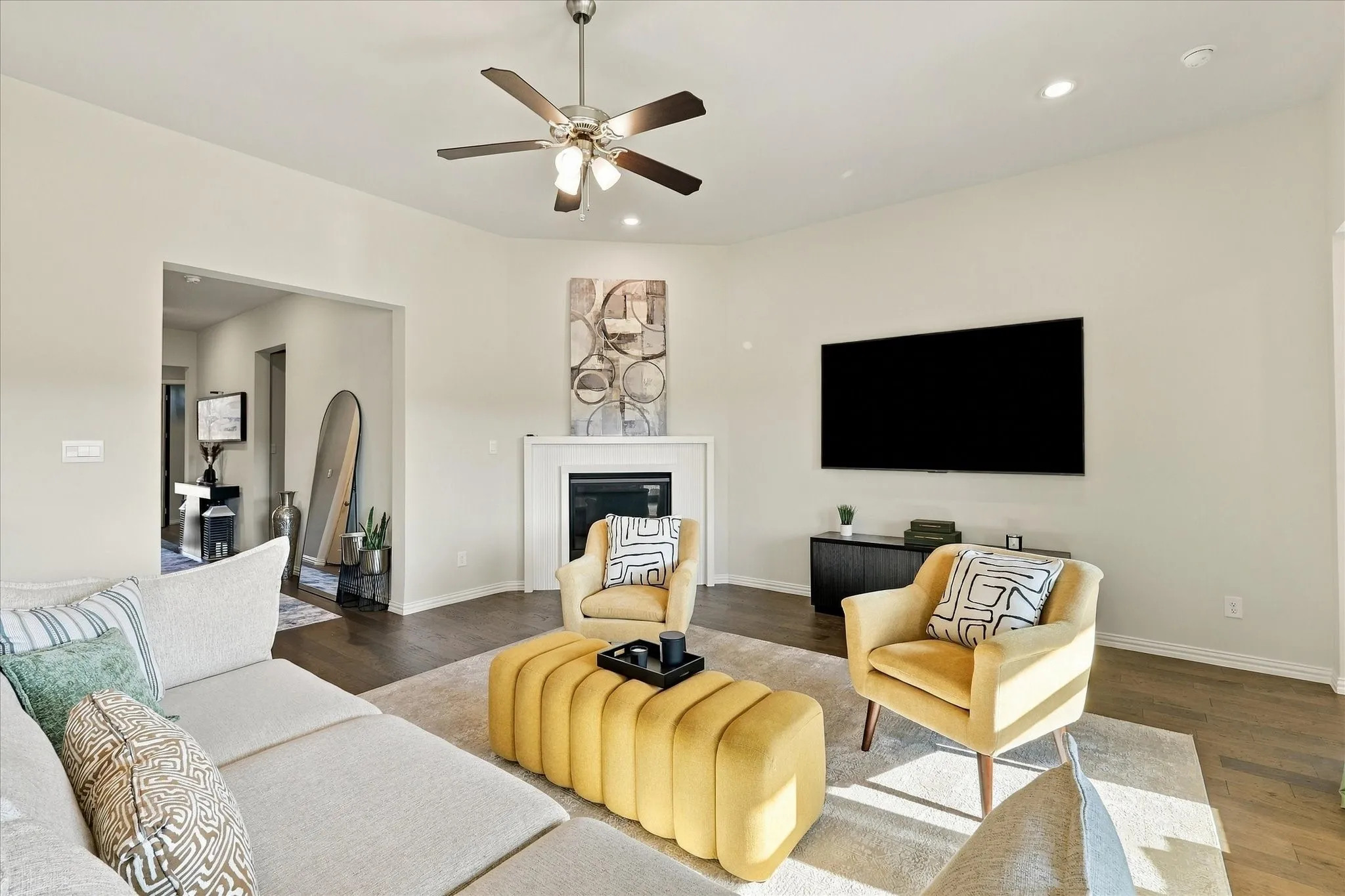Spacious living area featuring wood-finish flooring, a ceiling fan, recessed lighting, and a built-in fireplace with a mantel
