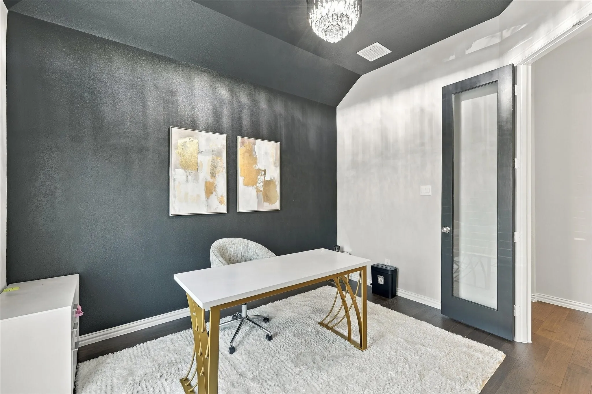 Vaulted ceiling with a chandelier, dark wood-finish flooring, and a glass-paneled door