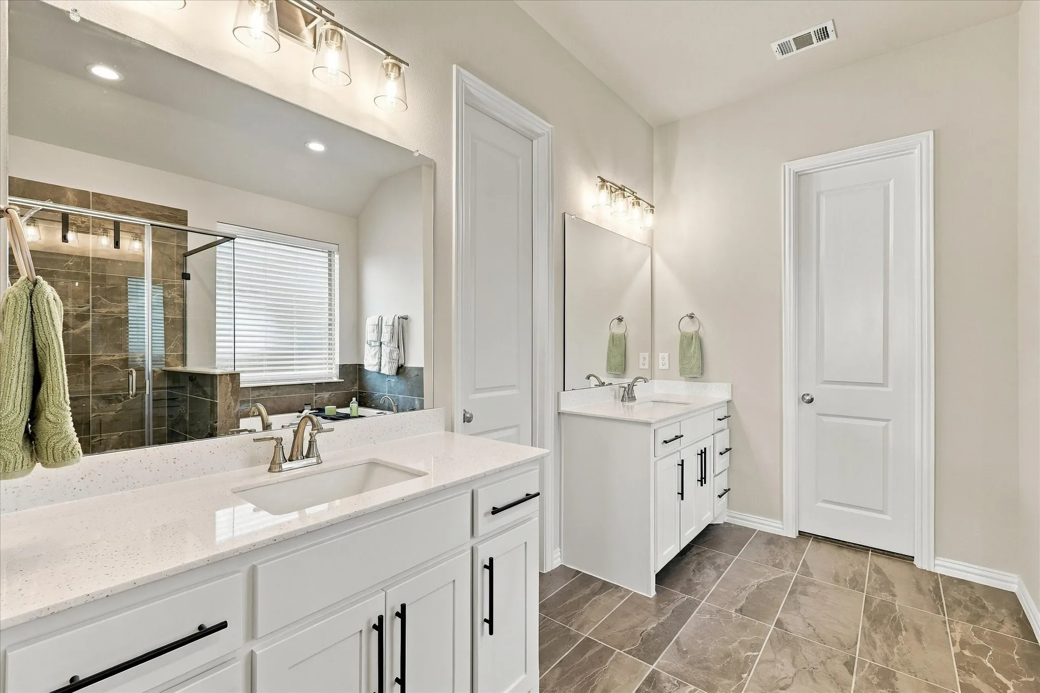 Dual vanity with white cabinetry, polished chrome fixtures, and quartz countertops