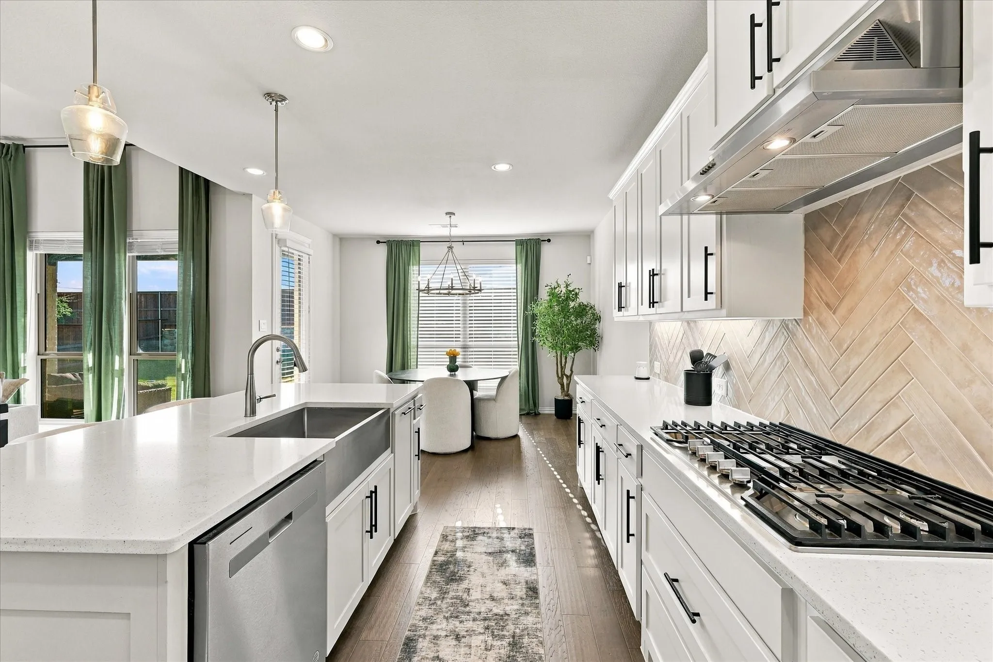 Kitchen featuring white shaker cabinetry, stainless steel appliances, wood-finish flooring, and a herringbone-patterned backsplash