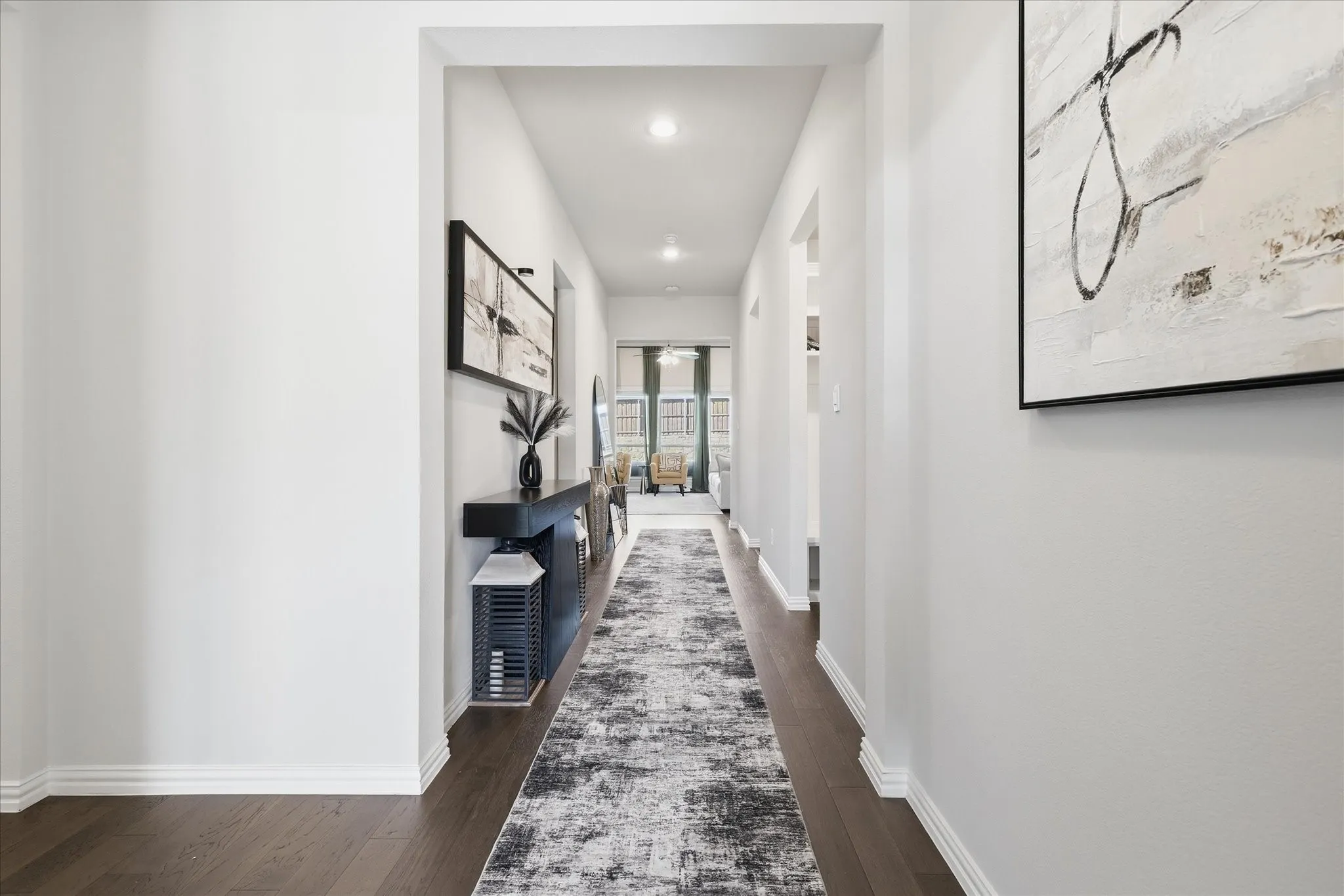 Elongated hallway with dark wood-finish flooring, recessed lighting, and bright white walls