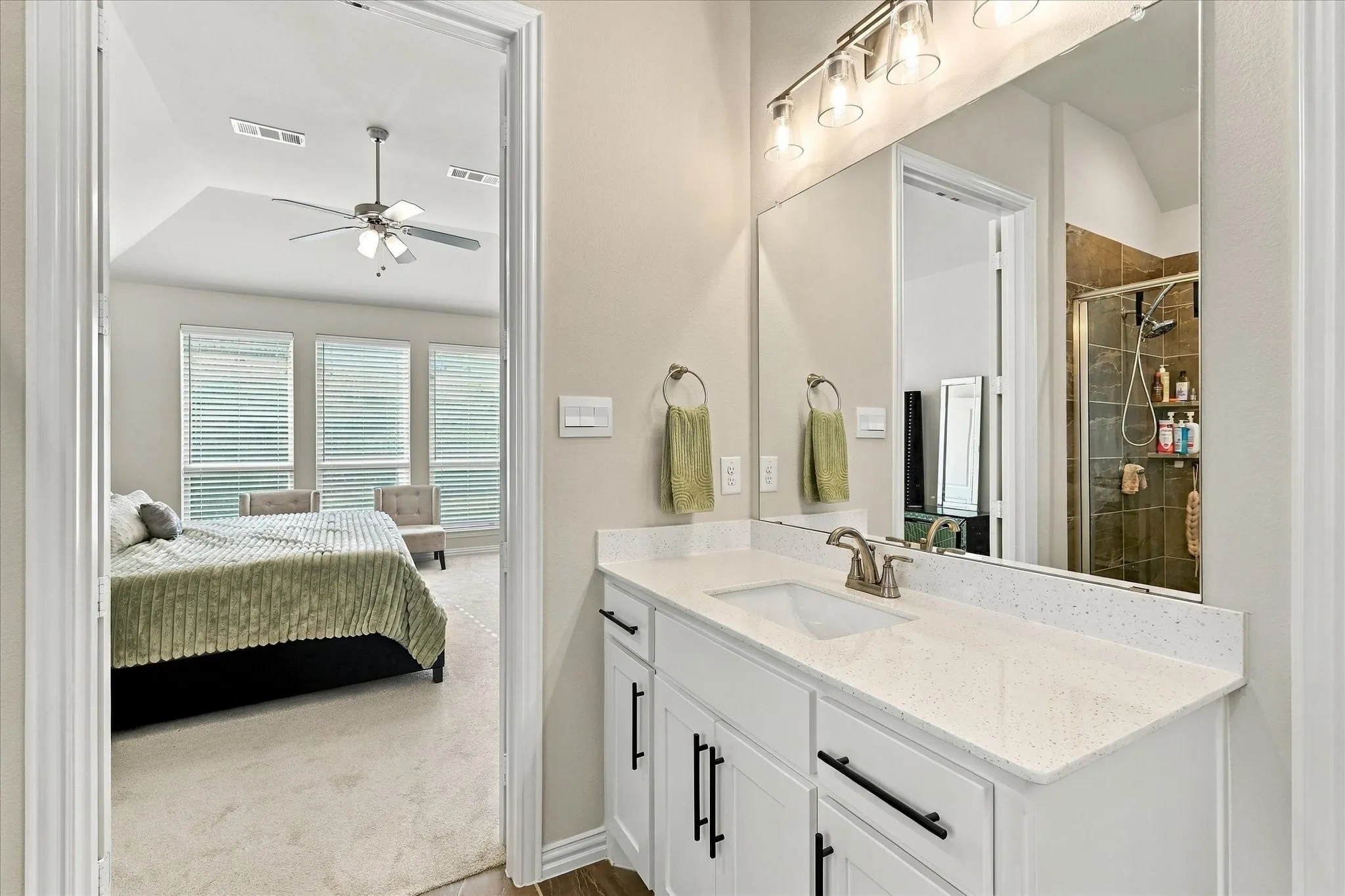 Vanity with a white countertop and integrated sink, complemented by a large wall-mounted mirror and brushed nickel fixtures