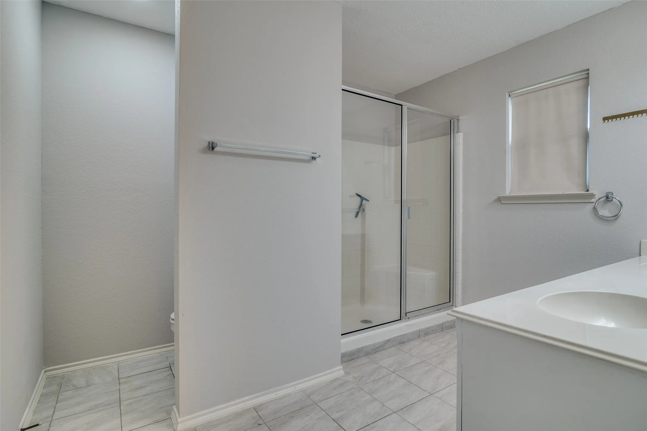 Bathroom featuring a walk-in shower with glass enclosure, single vanity with integrated sink, and tiled flooring