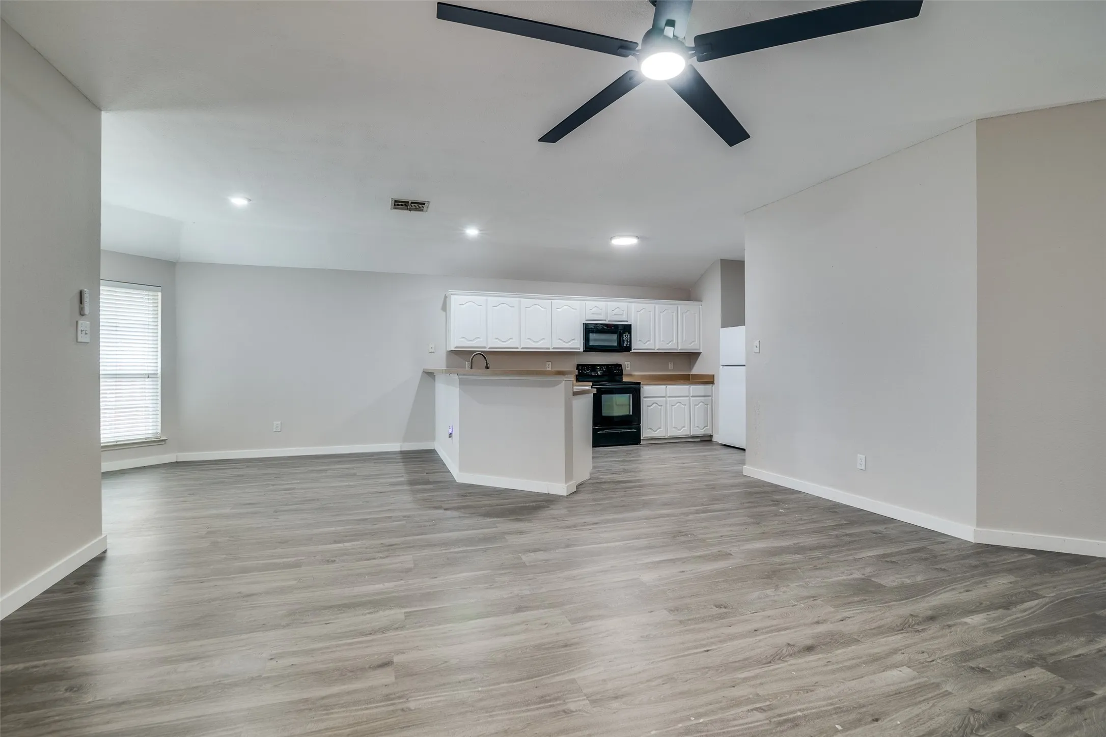 Open-concept living space featuring wood-finish flooring, recessed lighting, and a ceiling fan