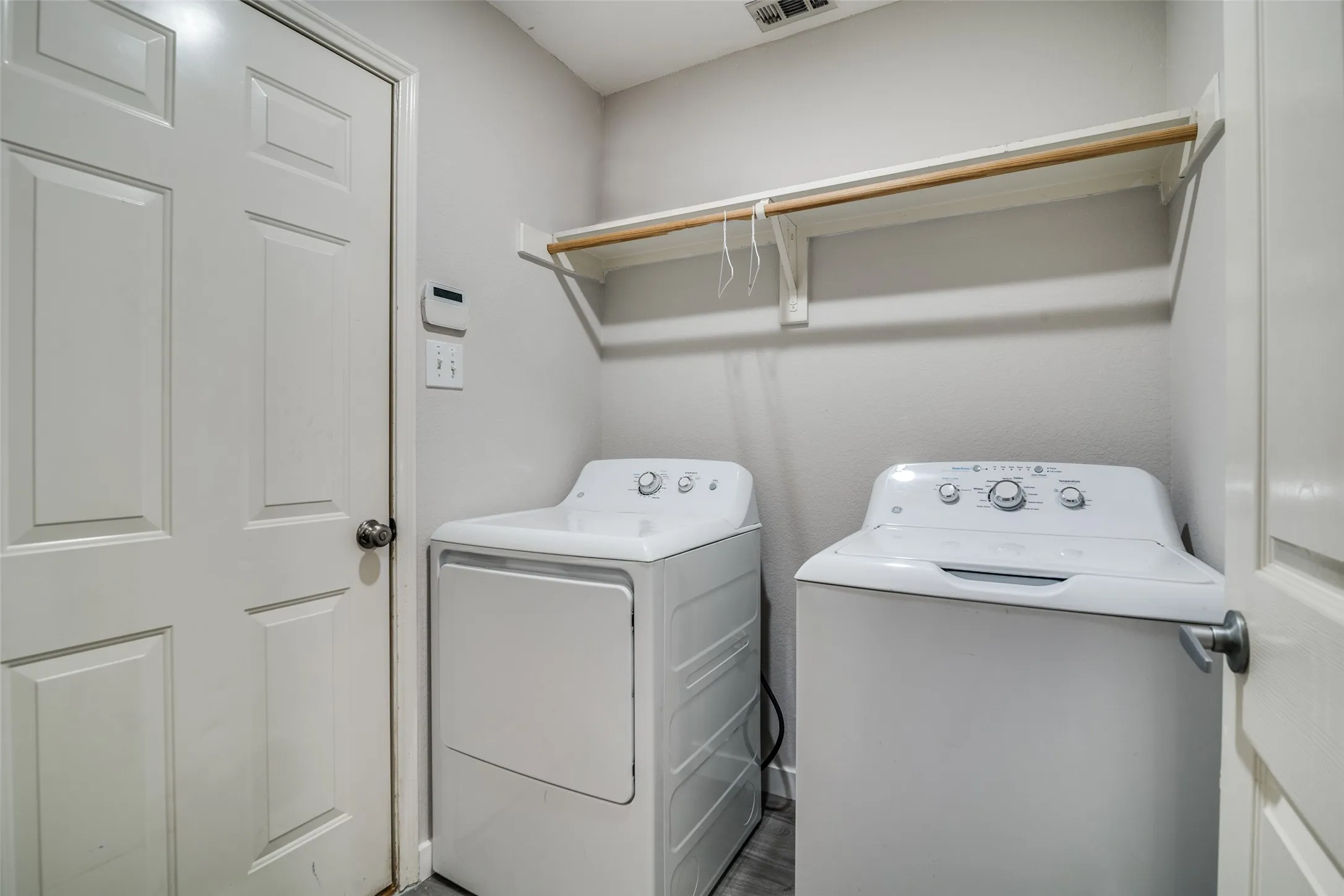 Dedicated laundry area featuring a built-in wood shelf with hanging rod