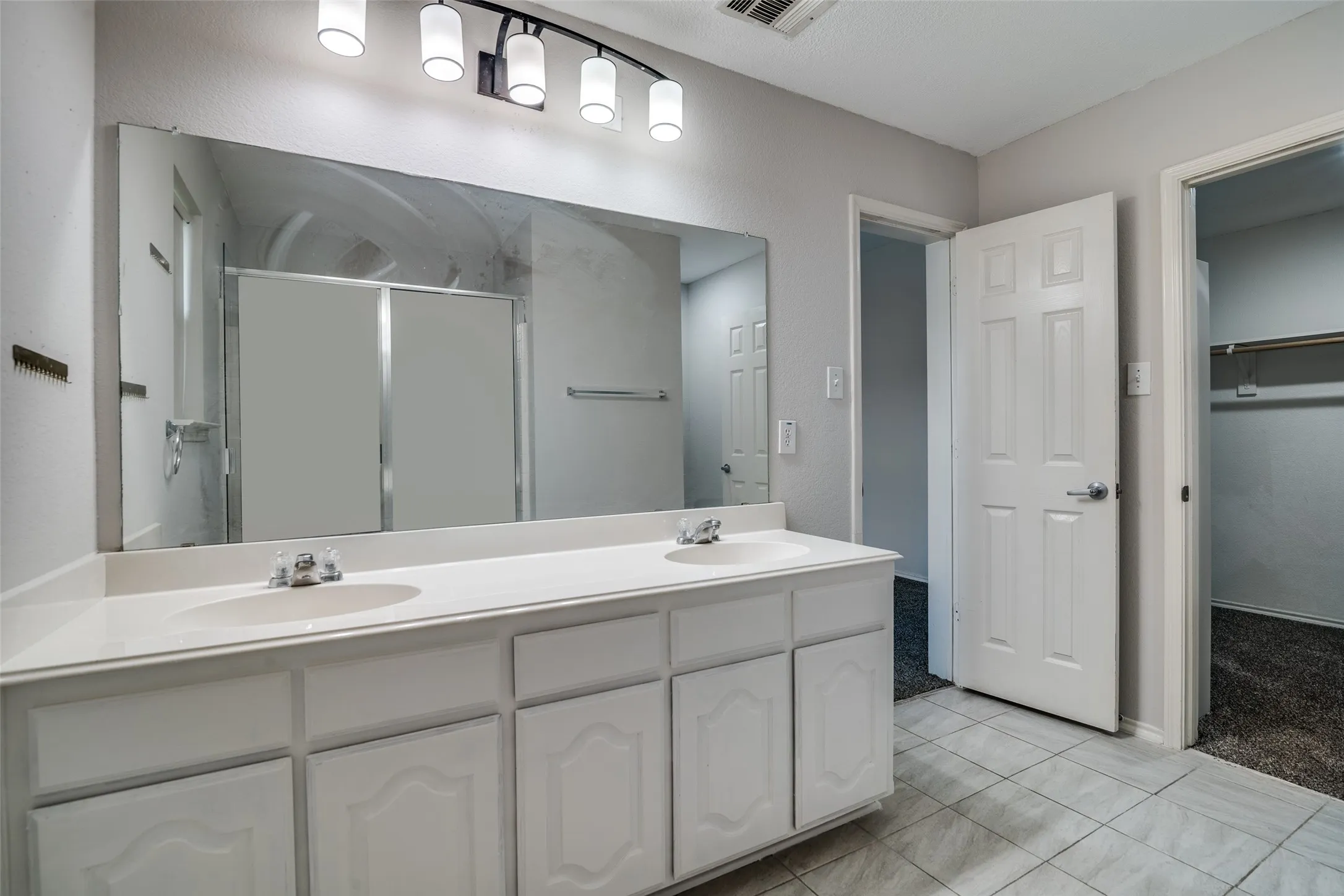 Dual vanity with white cabinetry and integrated sinks, complemented by an expansive mirror