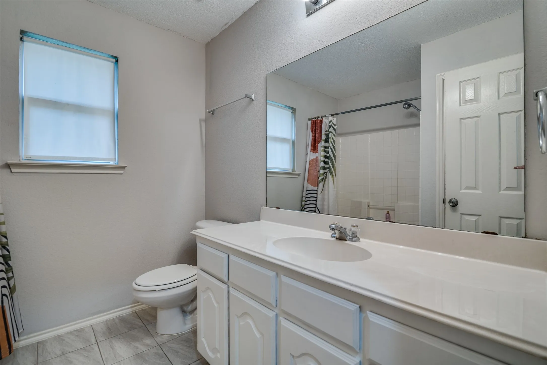 White vanity with cabinet storage, integrated sink, and a large wall-mounted mirror