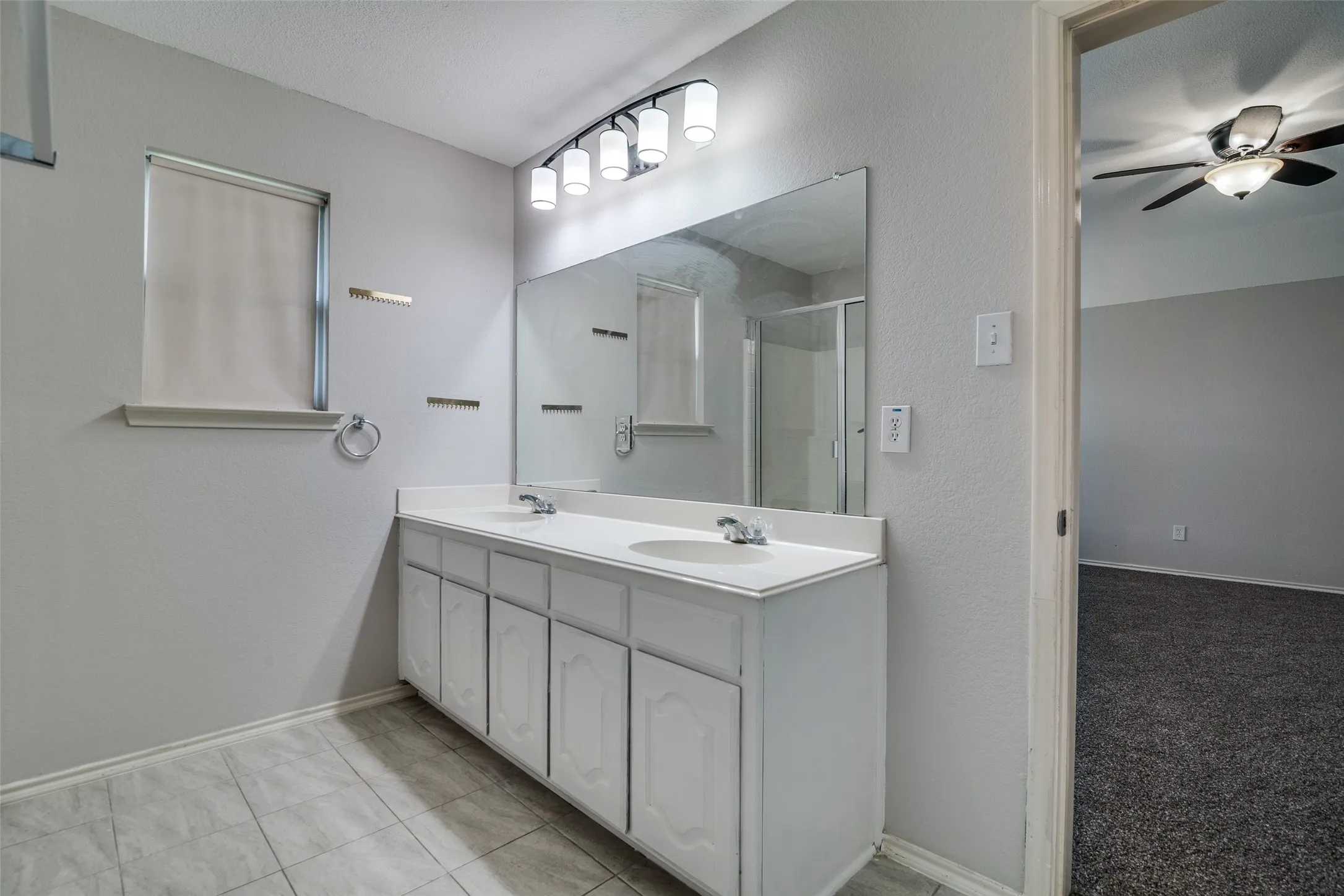 Bathroom featuring a dual vanity with integrated sinks, large mirror, and overhead four-light fixture