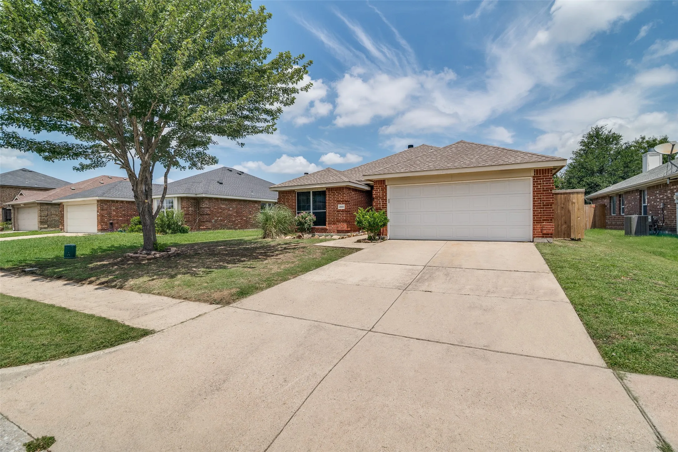 Brick exterior with an attached garage, concrete driveway, and a gabled roof