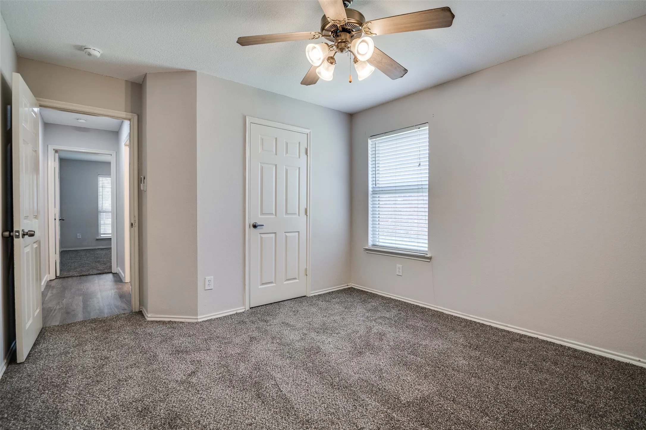 Neutral-toned walls, gray carpet flooring, ceiling fan with integrated lighting, window with horizontal blinds, and paneled interior doors