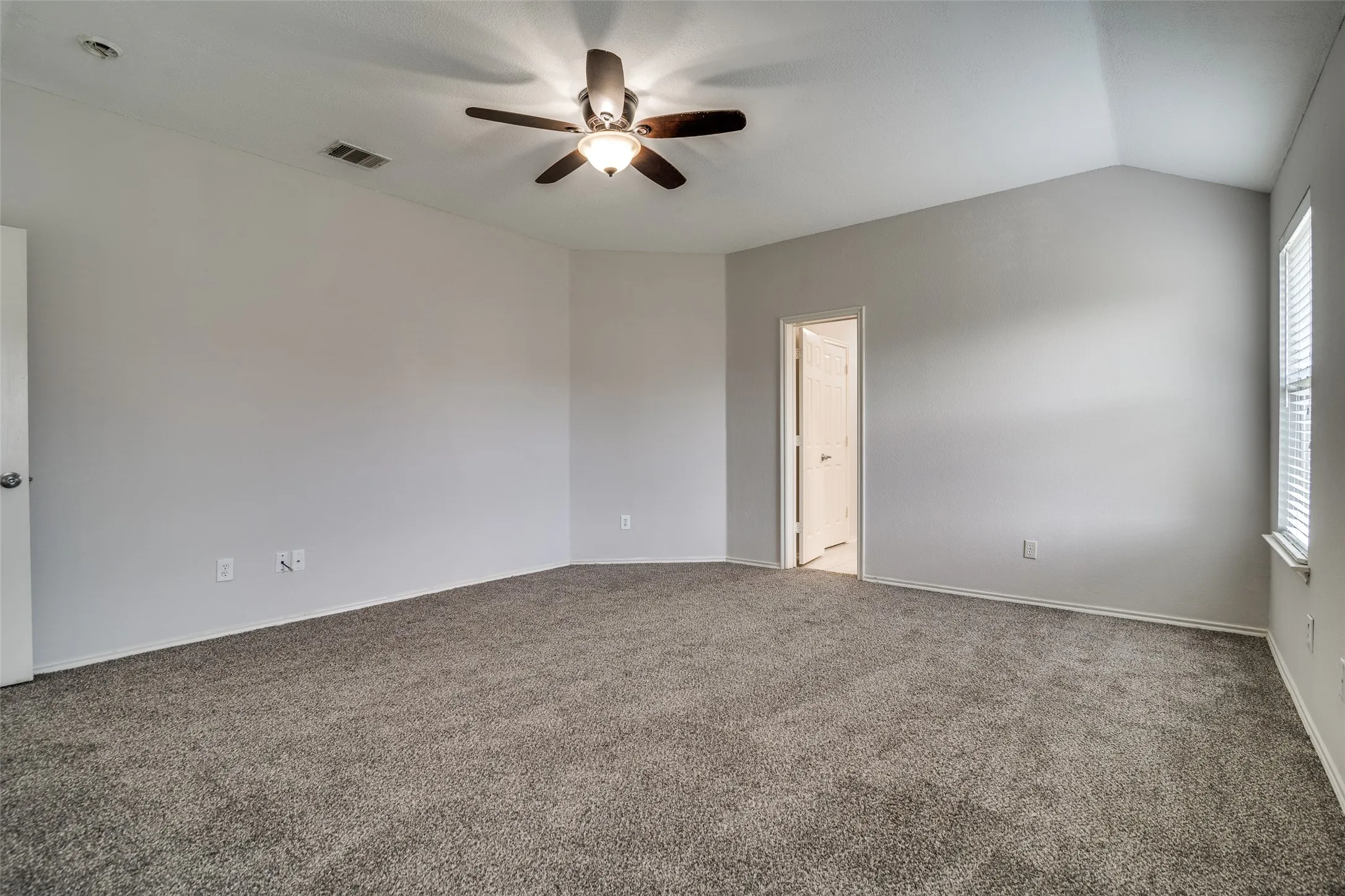 Vaulted ceiling, ceiling fan with light fixture, carpeted flooring, window with blinds
