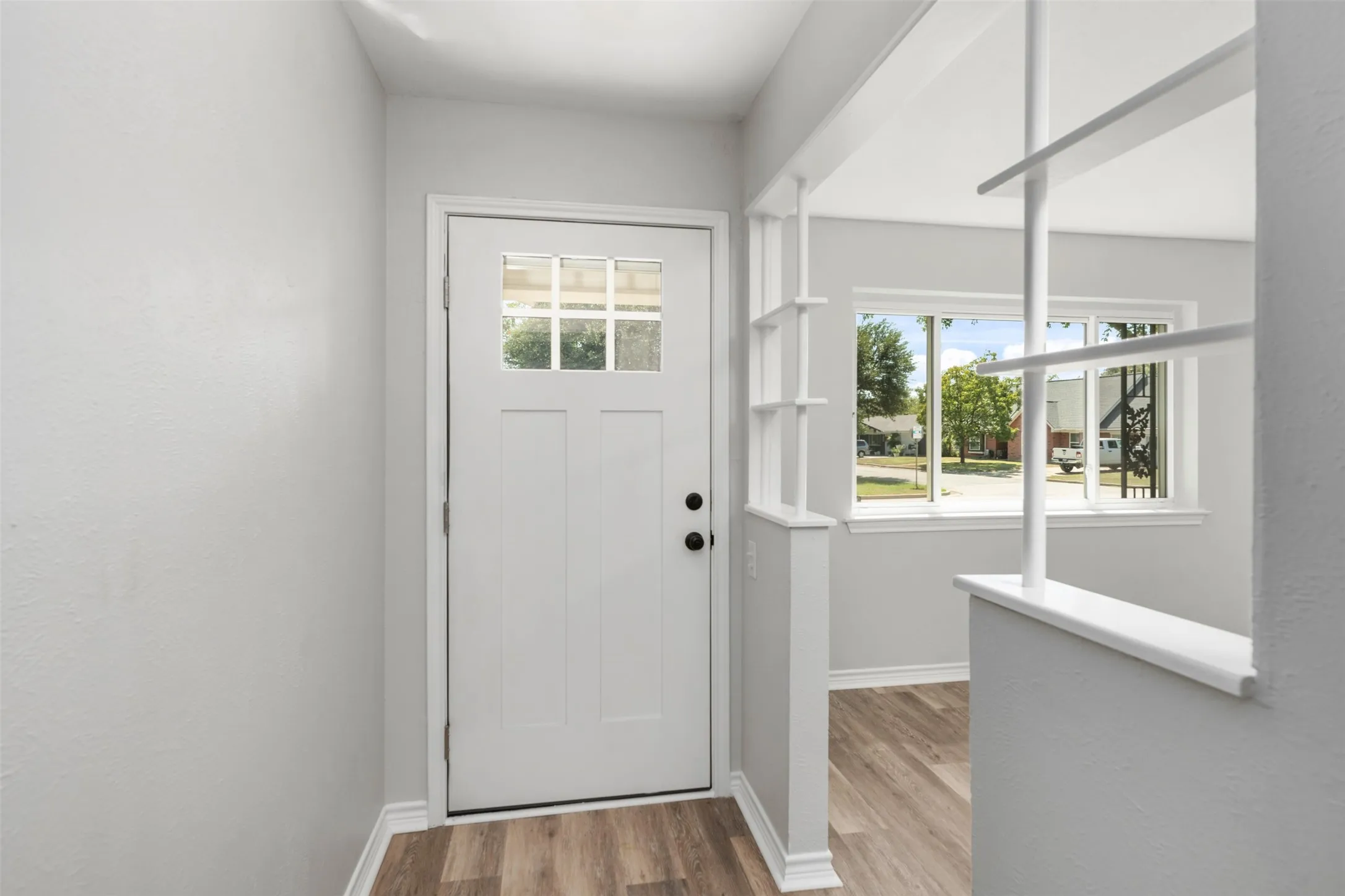 Entryway featuring a panel door with lites, wood-finish flooring, and decorative room divider
