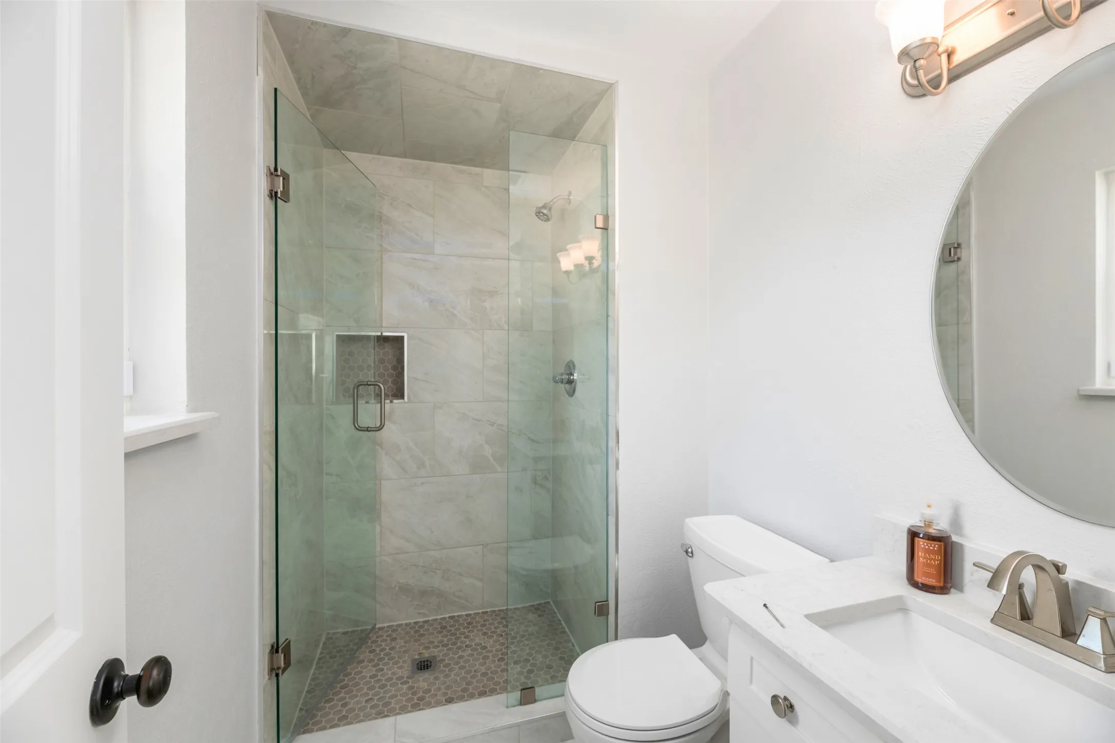 Glass-enclosed shower with tiled walls and a mosaic-tiled floor