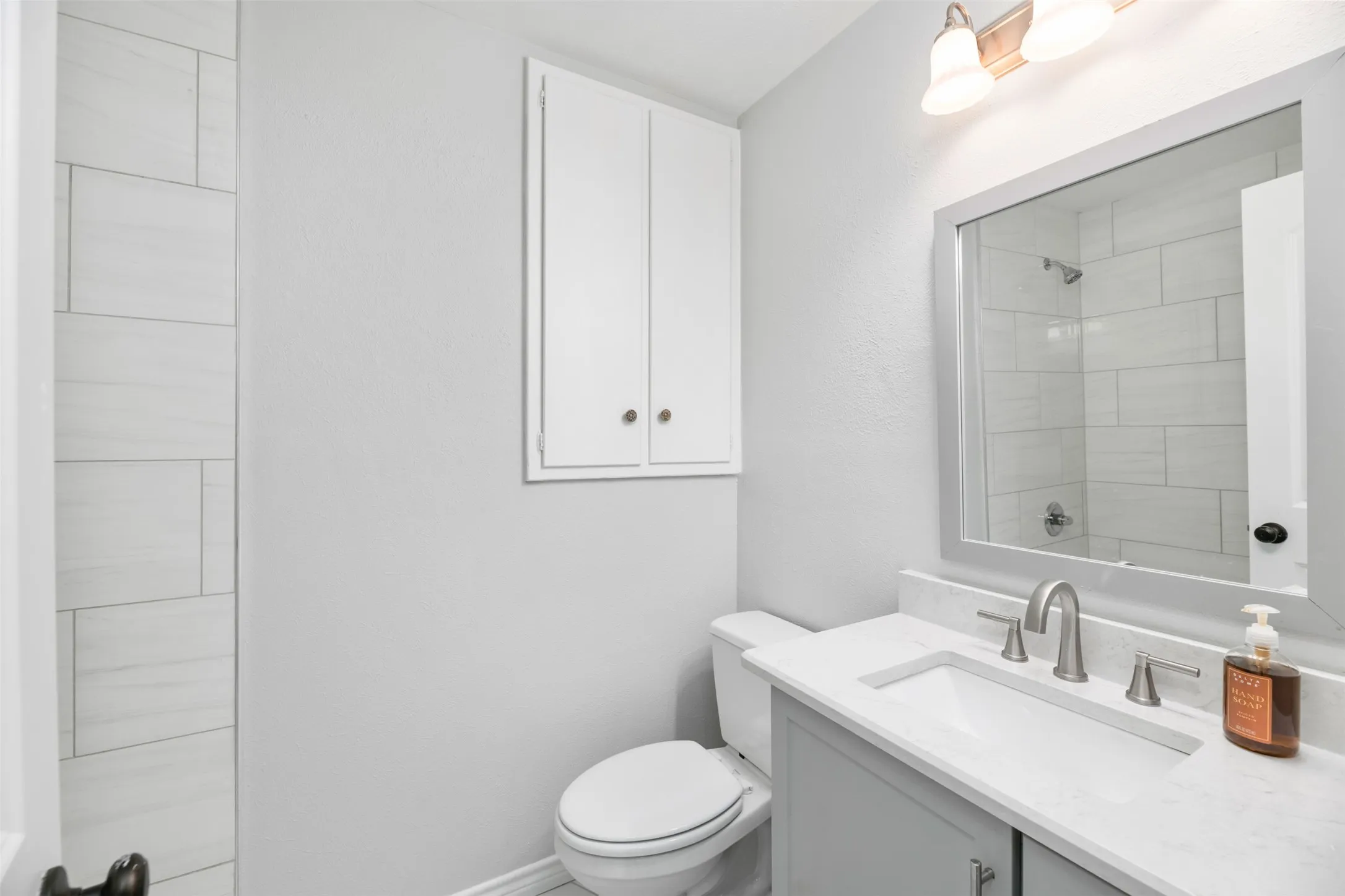 White vanity with stone-finish countertop, integrated sink, and brushed nickel fixtures