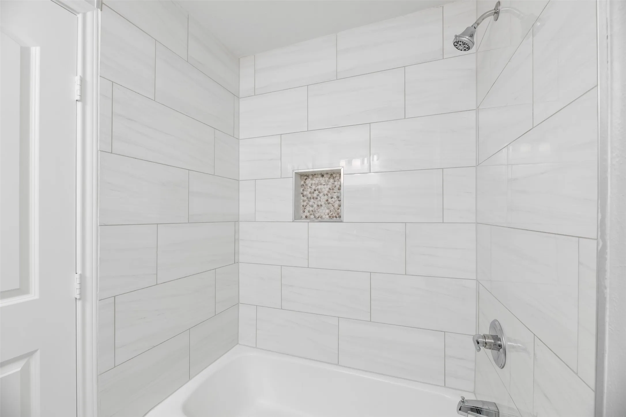 White subway tile shower surround with a built-in niche featuring mosaic tile