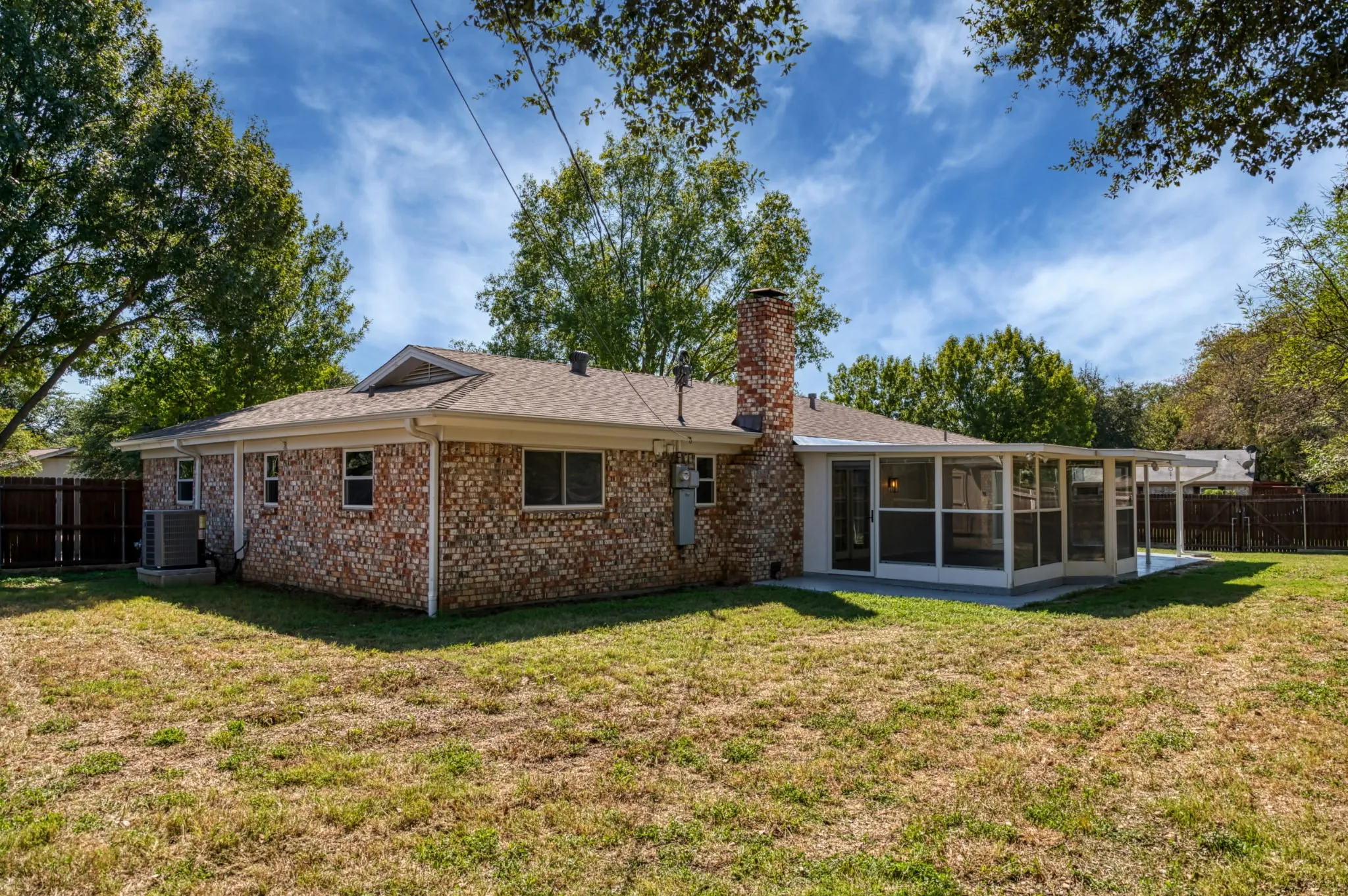 Brick exterior, screened enclosure, covered patio, exterior chimney, and a fenced perimeter