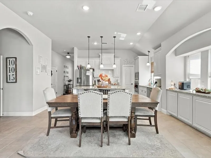 Arched entryways delineate spaces, complemented by recessed lighting and pendant fixtures