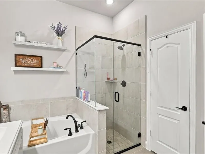 Enclosed shower with matte black hardware, tiled walls, and tiled flooring