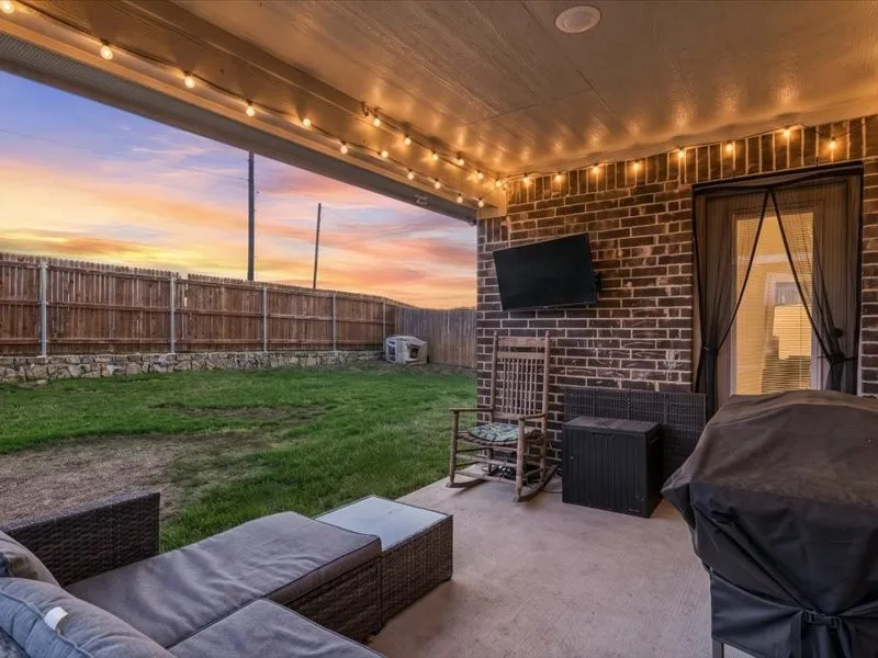 Covered patio with string lighting, exposed brick wall, and concrete flooring