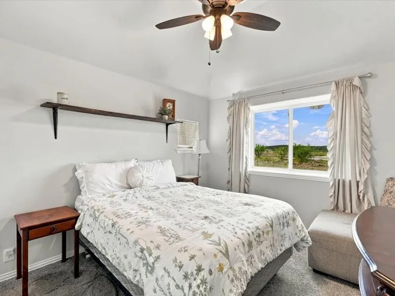 Vaulted ceiling featuring a ceiling fan with integrated lighting, a large window, and a built-in wall shelf with decorative brackets