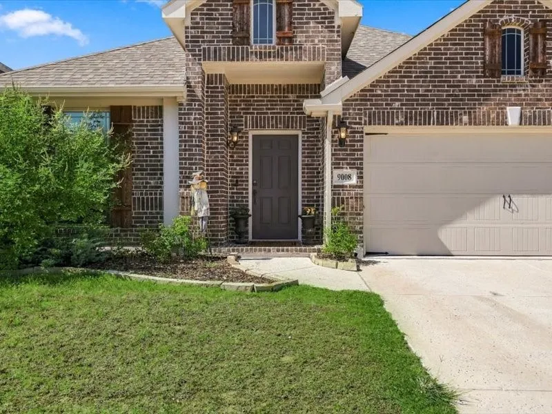 Brick exterior with a peaked roofline, attached garage, and a concrete driveway