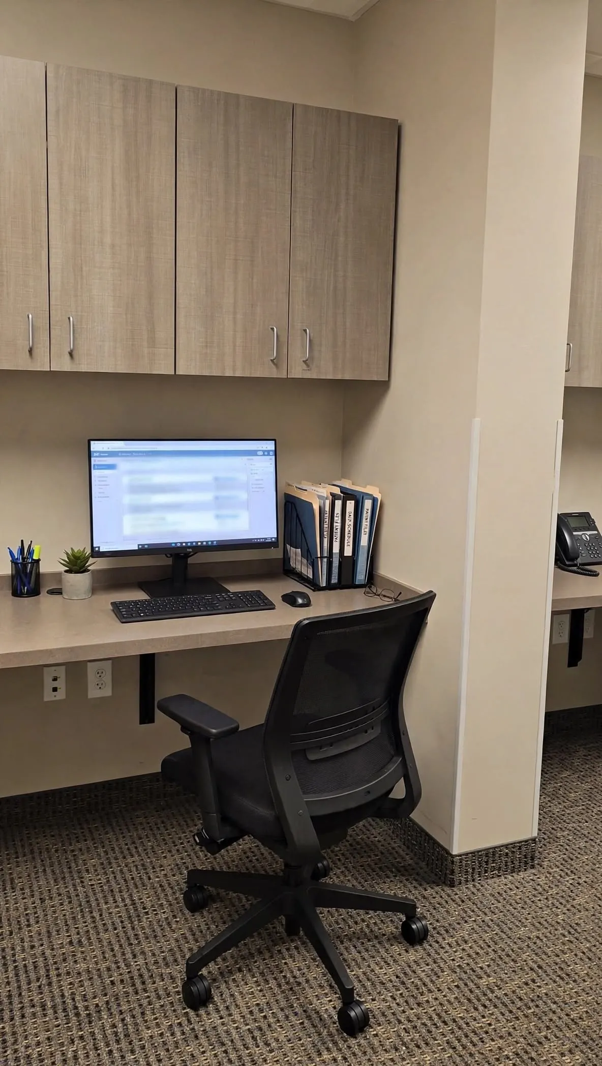 Built-in desk with overhead cabinetry, wall-mounted desk, and patterned carpet flooring