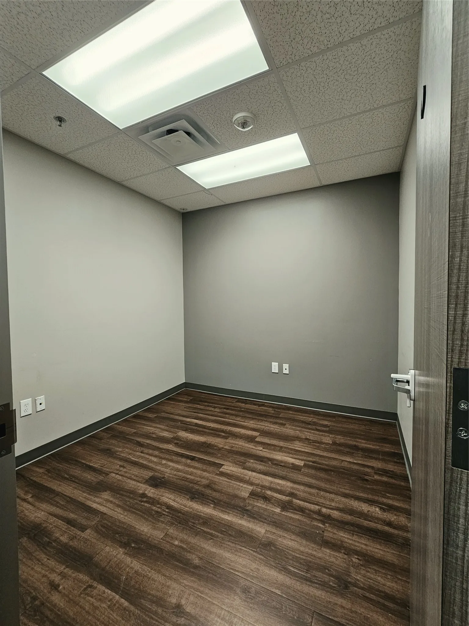Recessed lighting with a drop ceiling, wood-finish flooring, and neutral wall tones