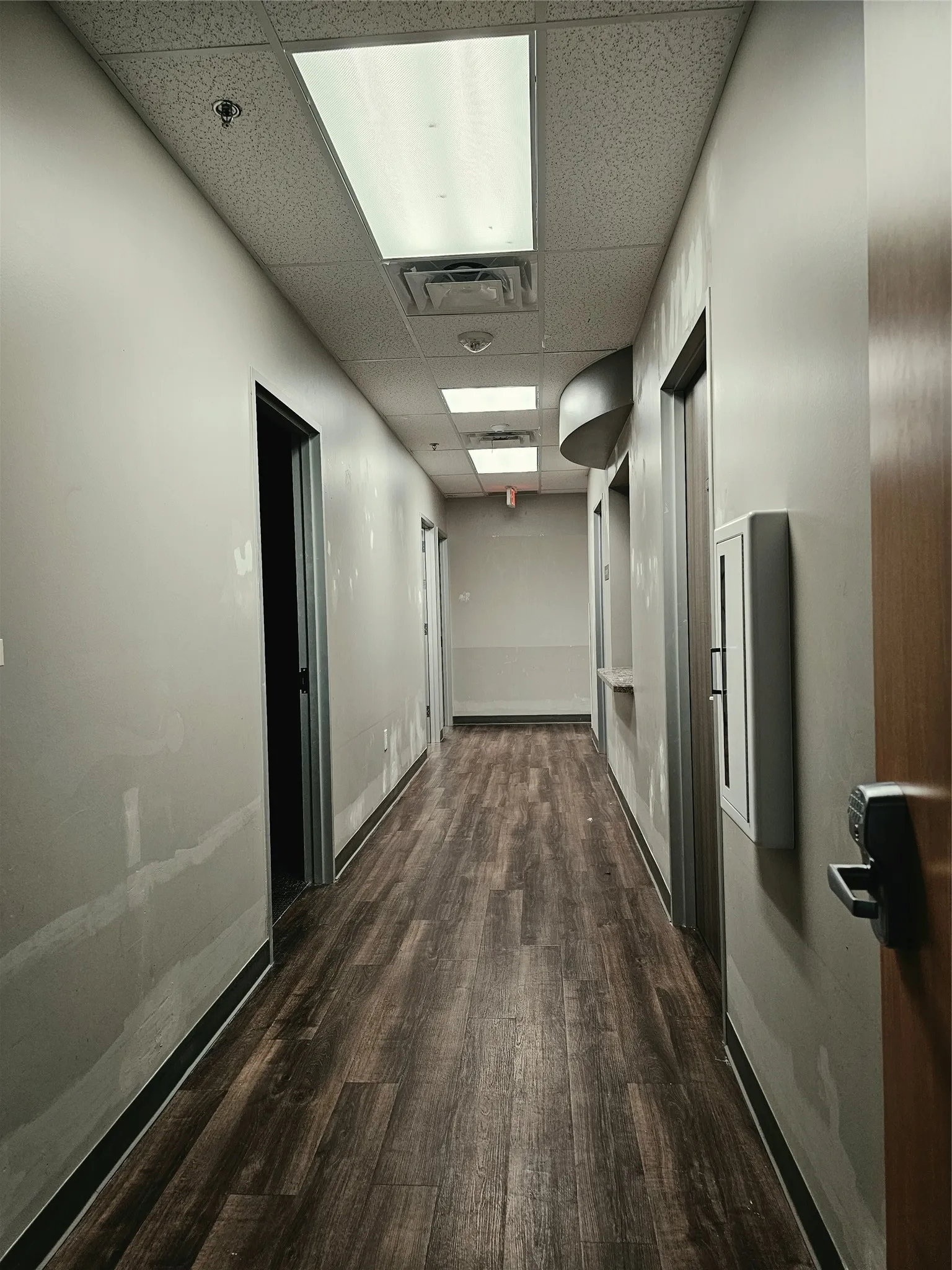 Wood-finish flooring, drop ceiling with recessed lighting, and neutral wall tones