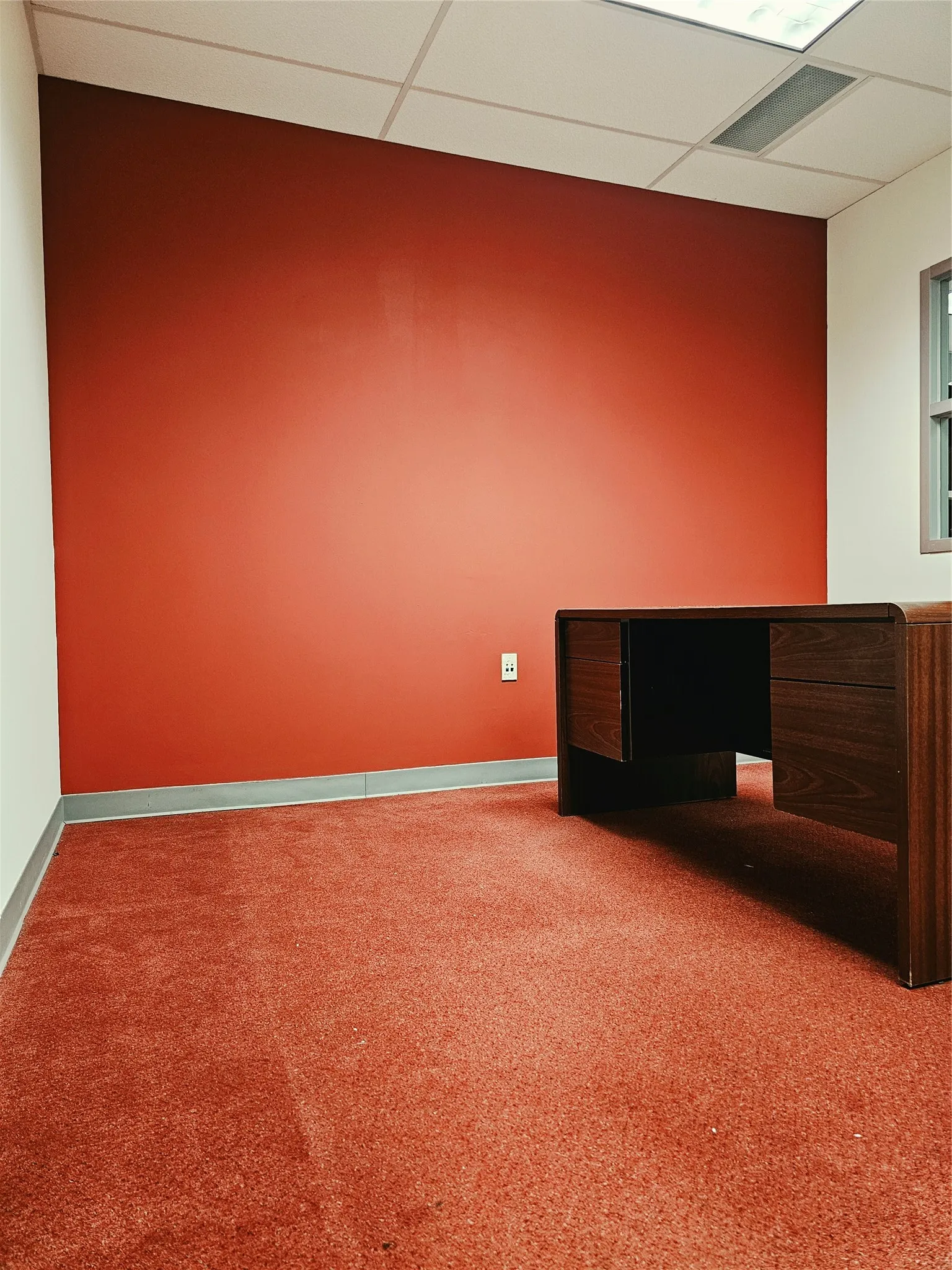 Recessed ceiling lighting with a grid-patterned tile ceiling, red accent wall, and wall-to-wall carpeting