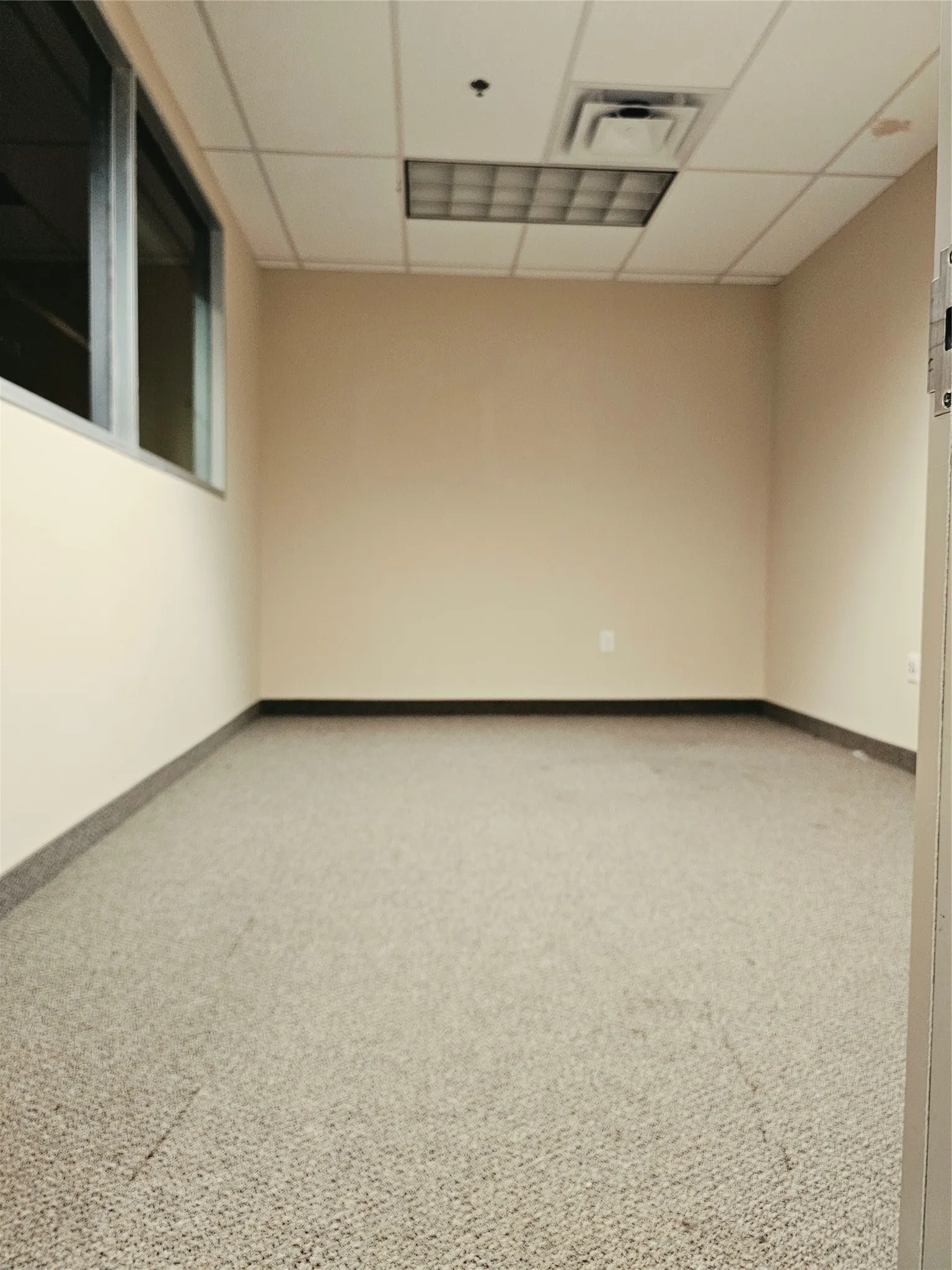 Recessed lighting, drop ceiling, wall-mounted window, light-colored walls, and carpeted flooring