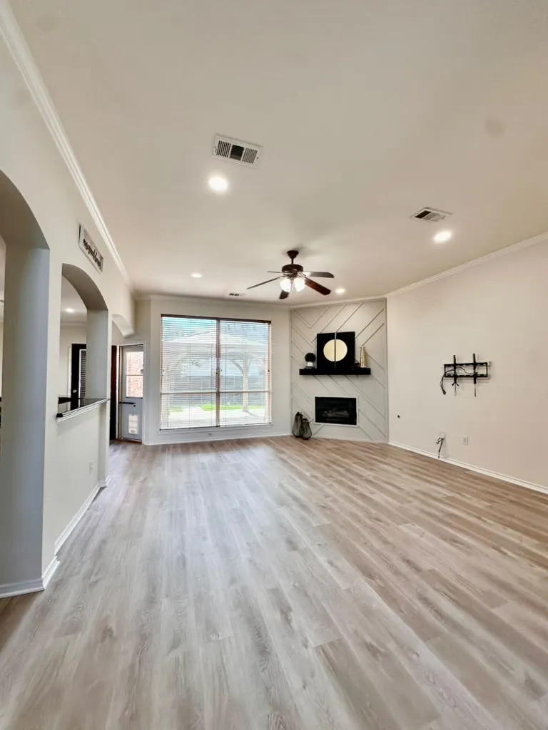 Living area featuring wood-finish flooring, recessed lighting, ceiling fan, and corner fireplace with decorative wall paneling and a floating mantel