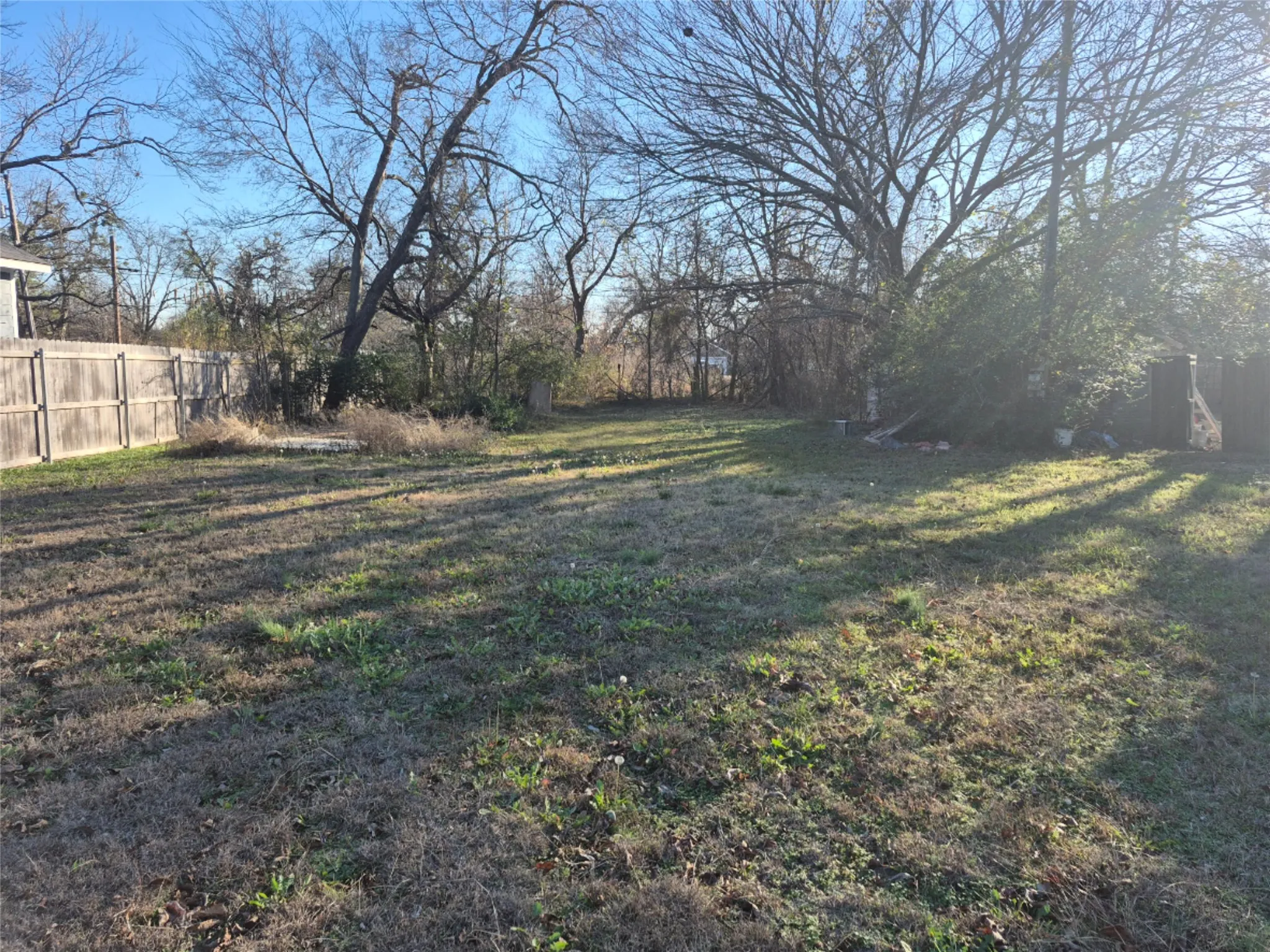 Expansive yard featuring mature trees, a wood privacy fence, and open grassy areas