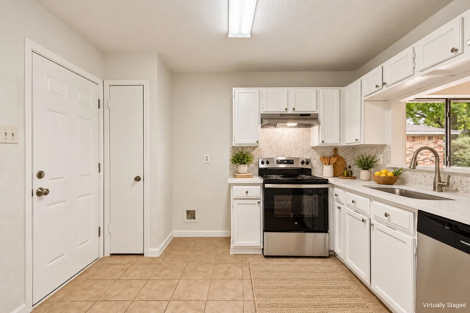 White cabinetry with brushed nickel hardware, light-toned backsplash, stainless steel appliances, and a window above the sink