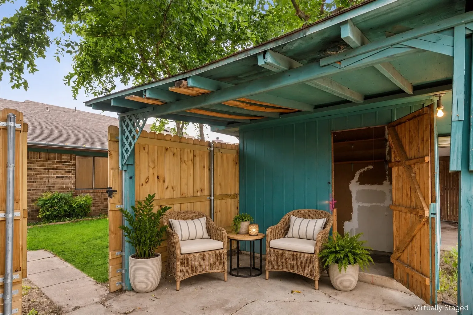 Covered patio area featuring a wooden privacy fence, concrete flooring, and a shed with double wooden doors