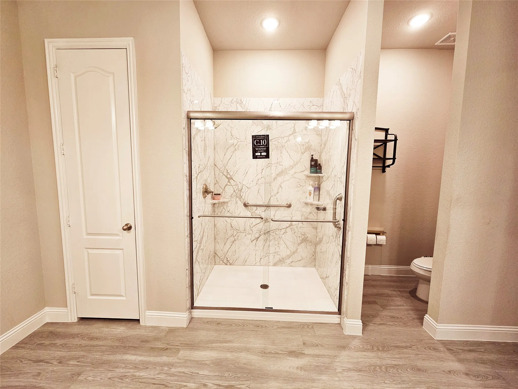 Spacious walk-in shower with glass enclosure, integrated shelving, and marble-look wall surround