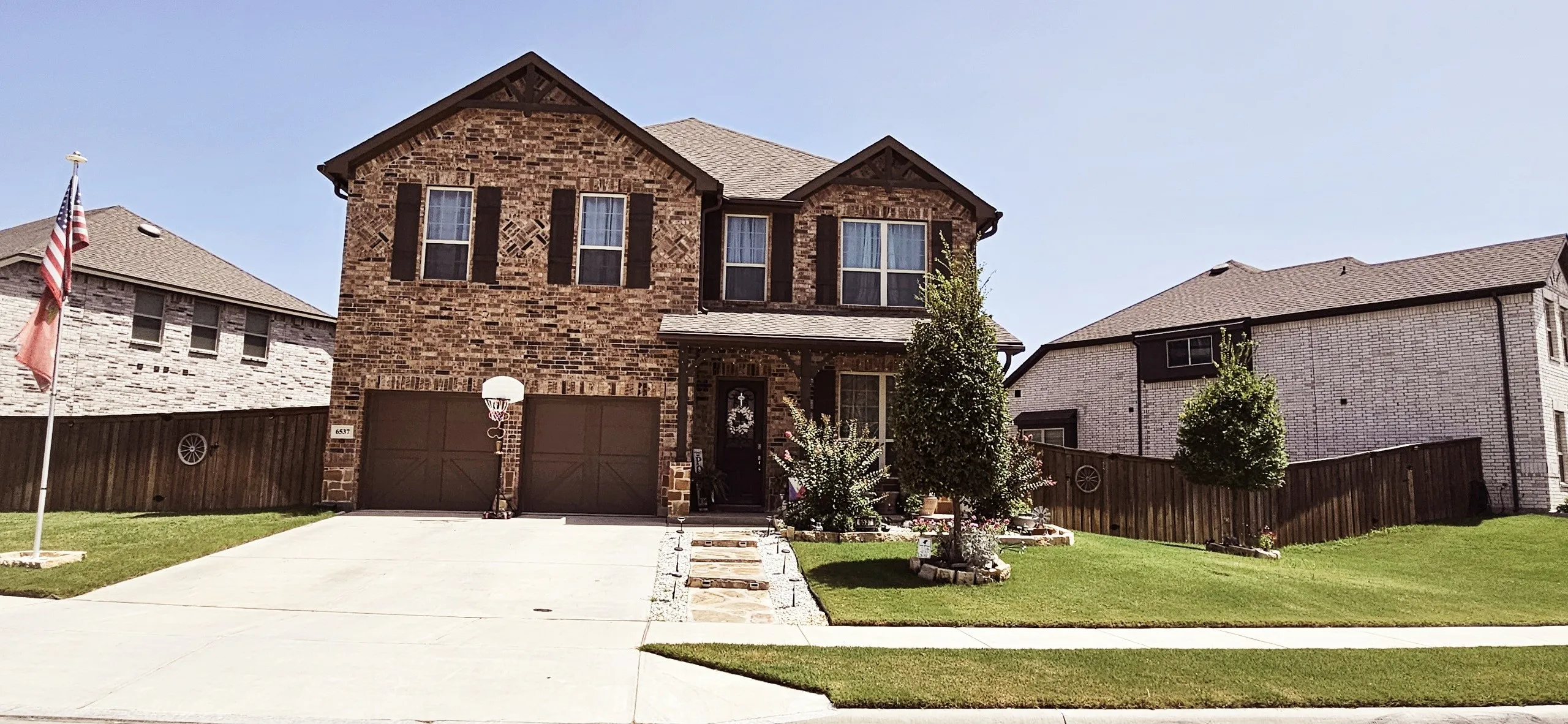 Brick exterior with dark shutters, covered front entry, and a two-car garage