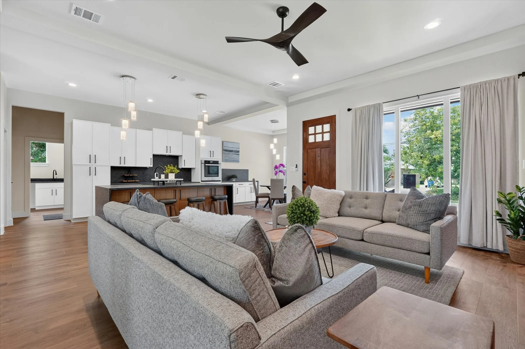 Open-concept living area featuring wood-finish flooring, a contemporary ceiling fan, and recessed lighting
