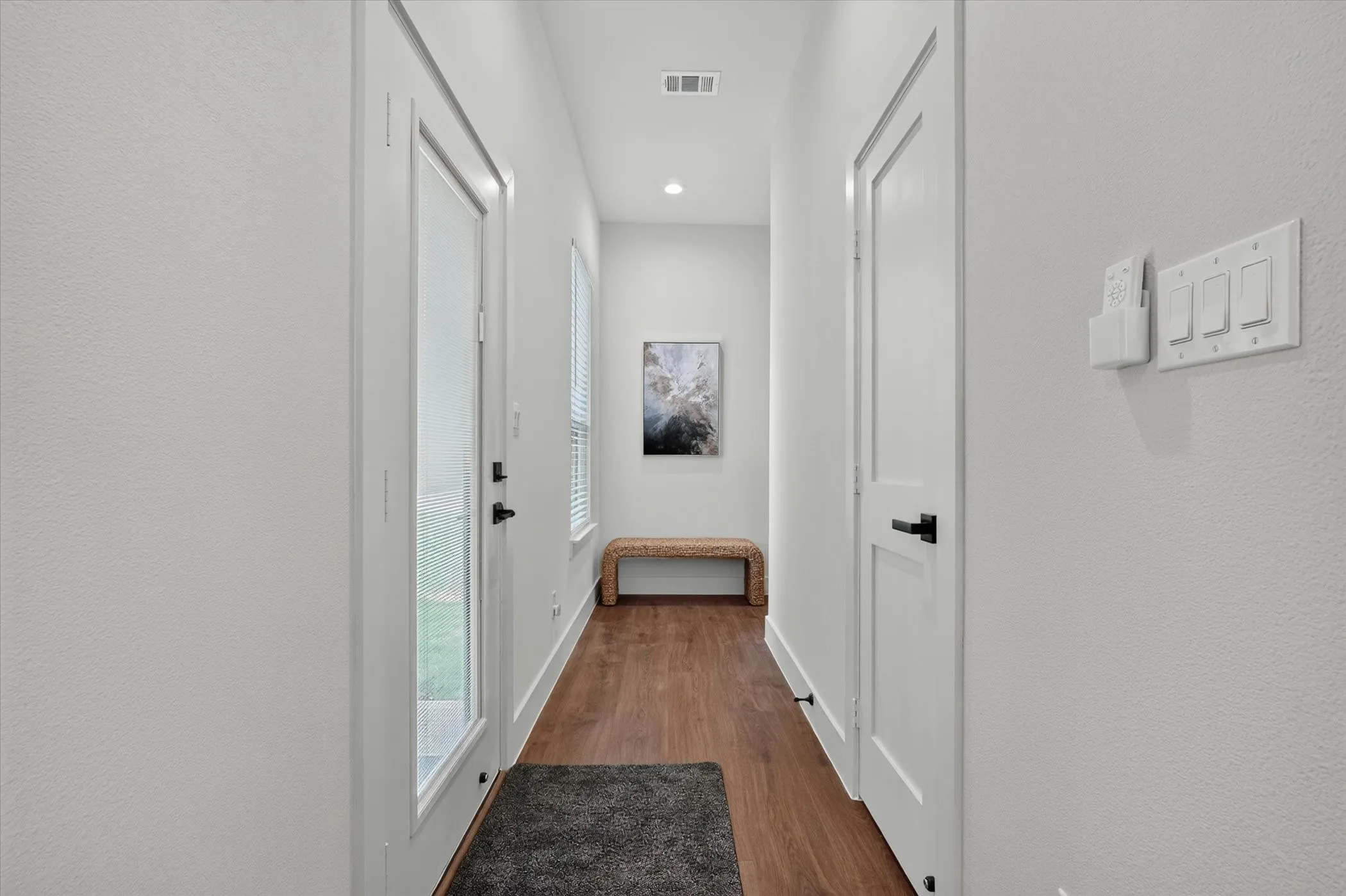 Wood-finish flooring, recessed lighting, and a modern white door with clear glass