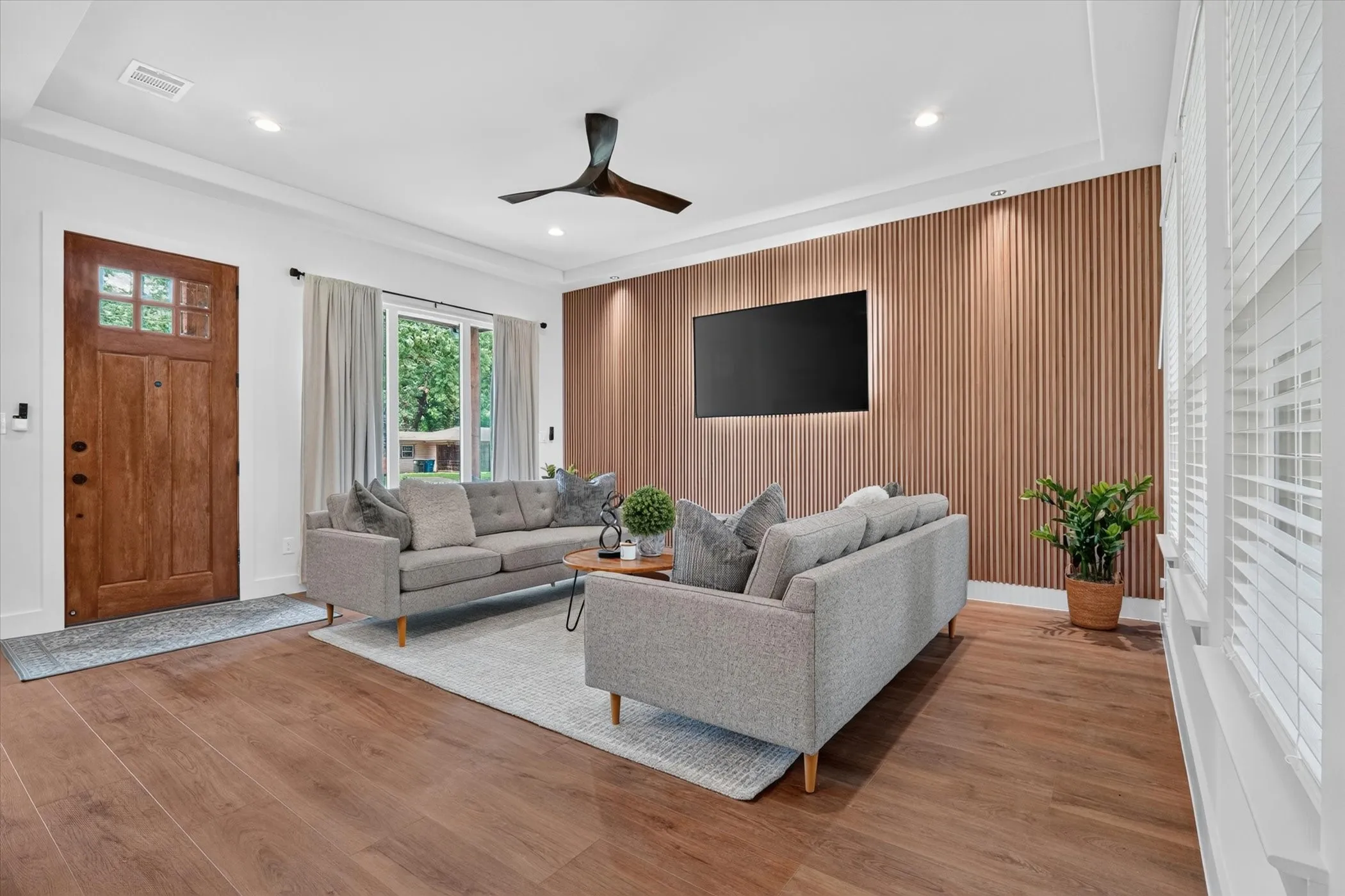 Wood-finish flooring, recessed lighting, ceiling fan, and a wood-paneled accent wall with integrated backlighting