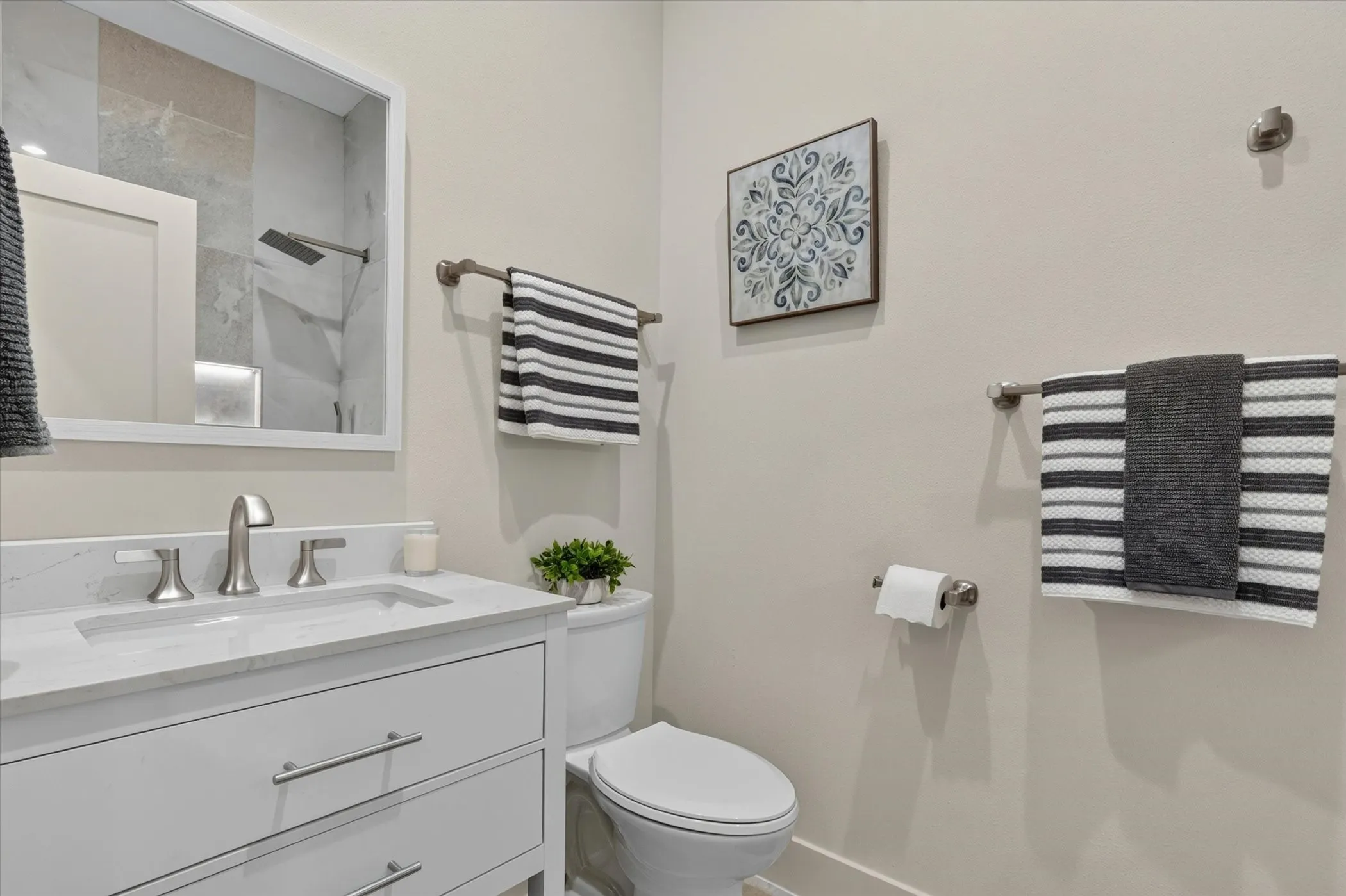White vanity with brushed nickel hardware, undermount sink, and a light-colored countertop