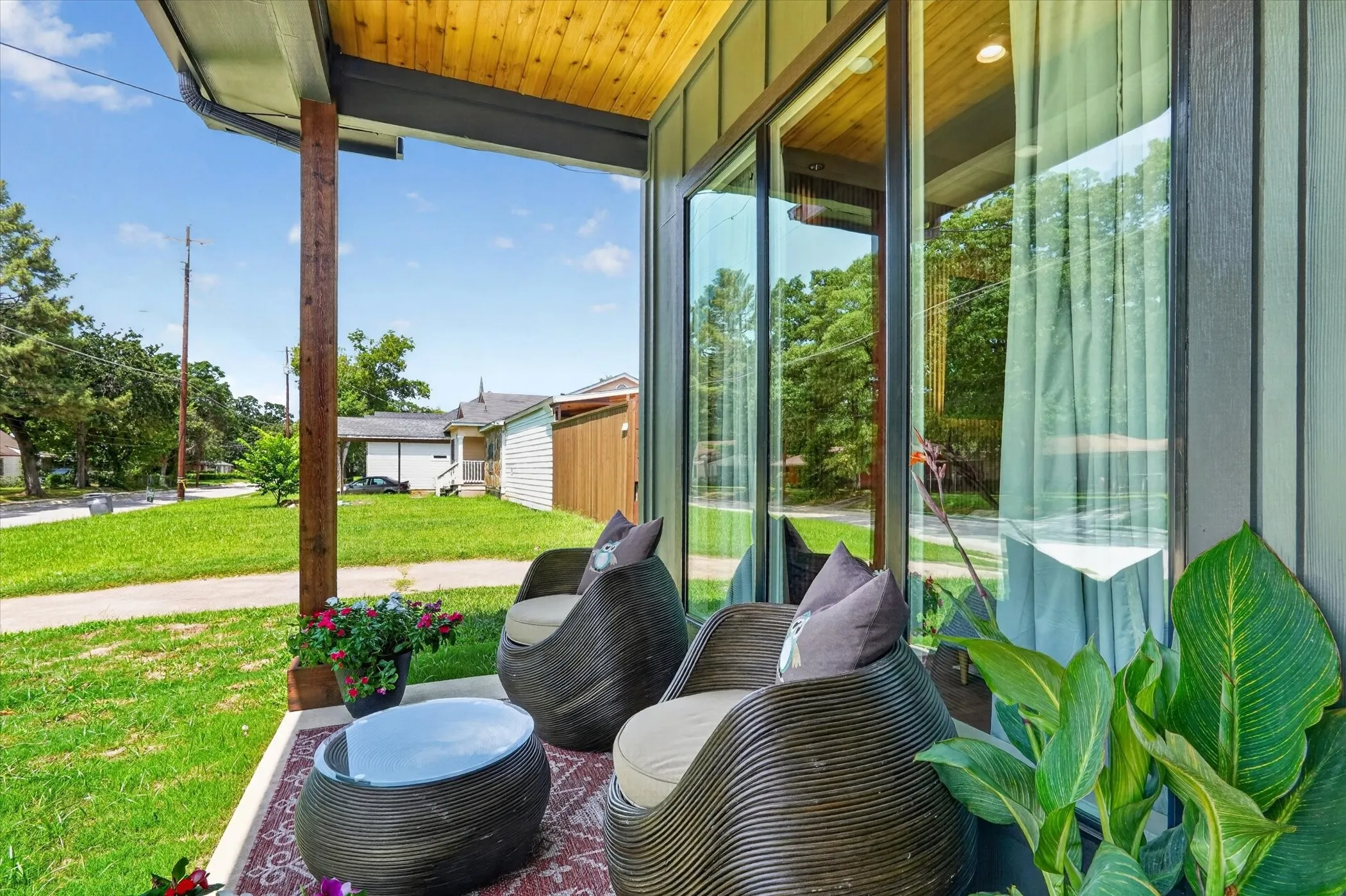 Covered porch with wood ceiling and support posts, featuring a large glass panel door and siding exterior