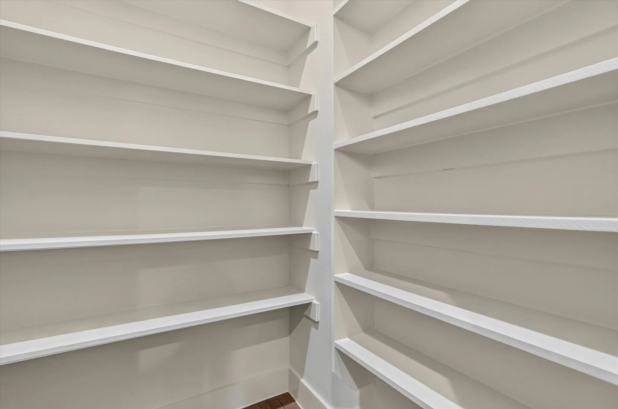 Built-in shelving with multiple white shelves and light-toned walls