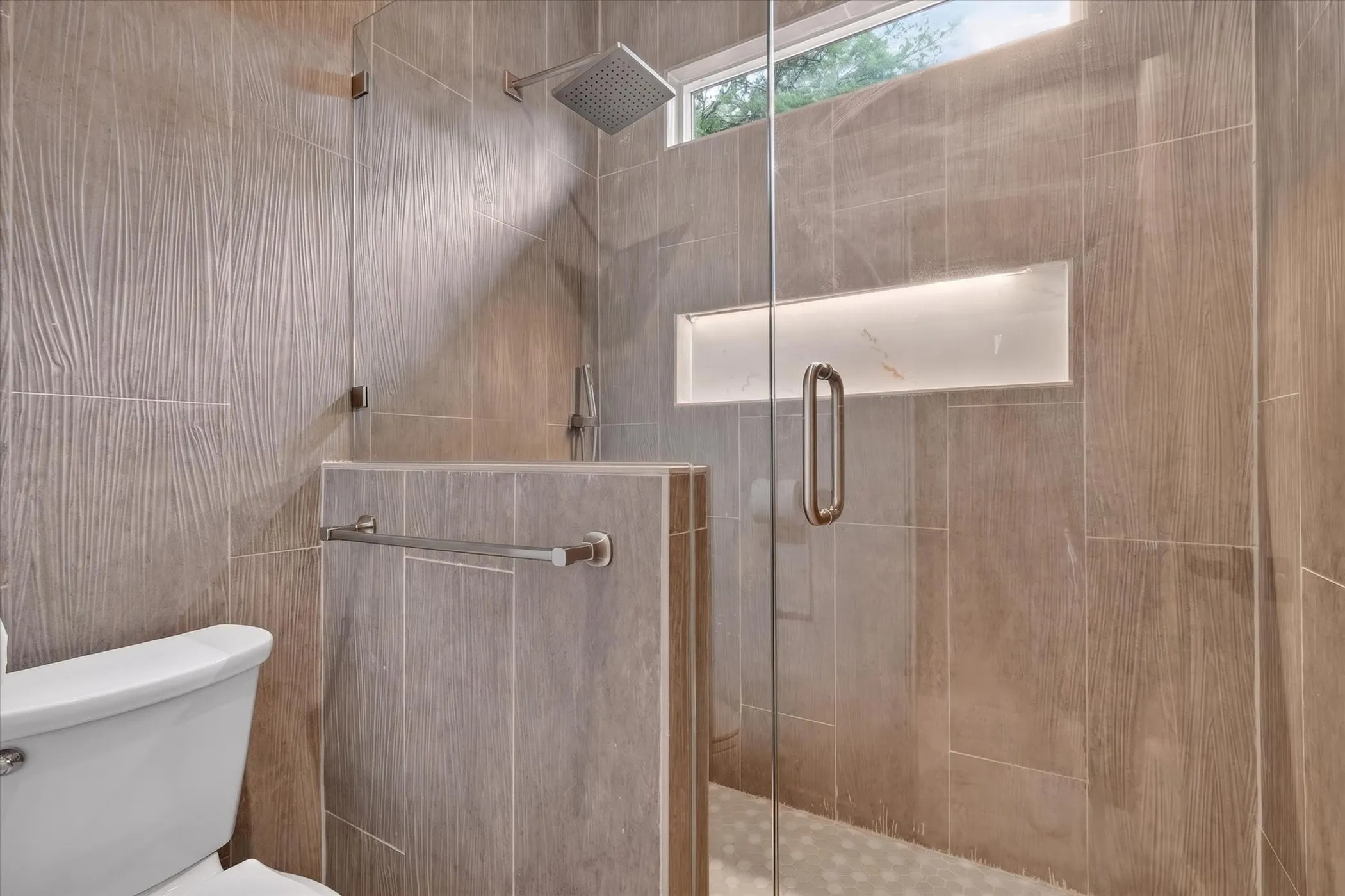 Walk-in shower with clear glass enclosure and overhead rainfall showerhead