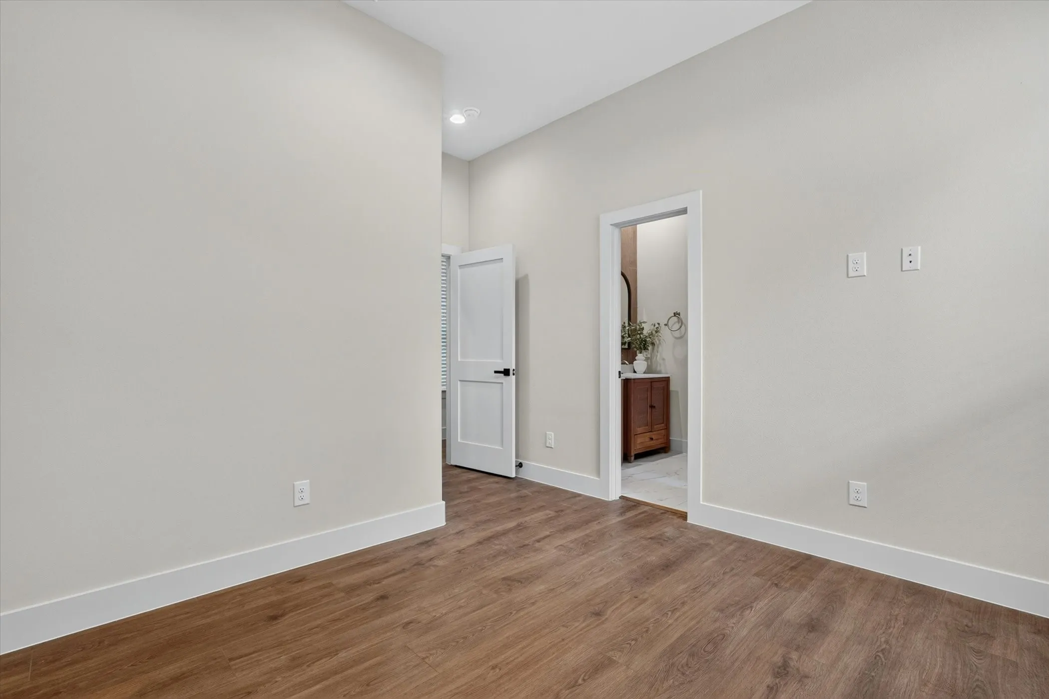 Wood-finish flooring, white trim, recessed lighting, and a white interior door with black hardware
